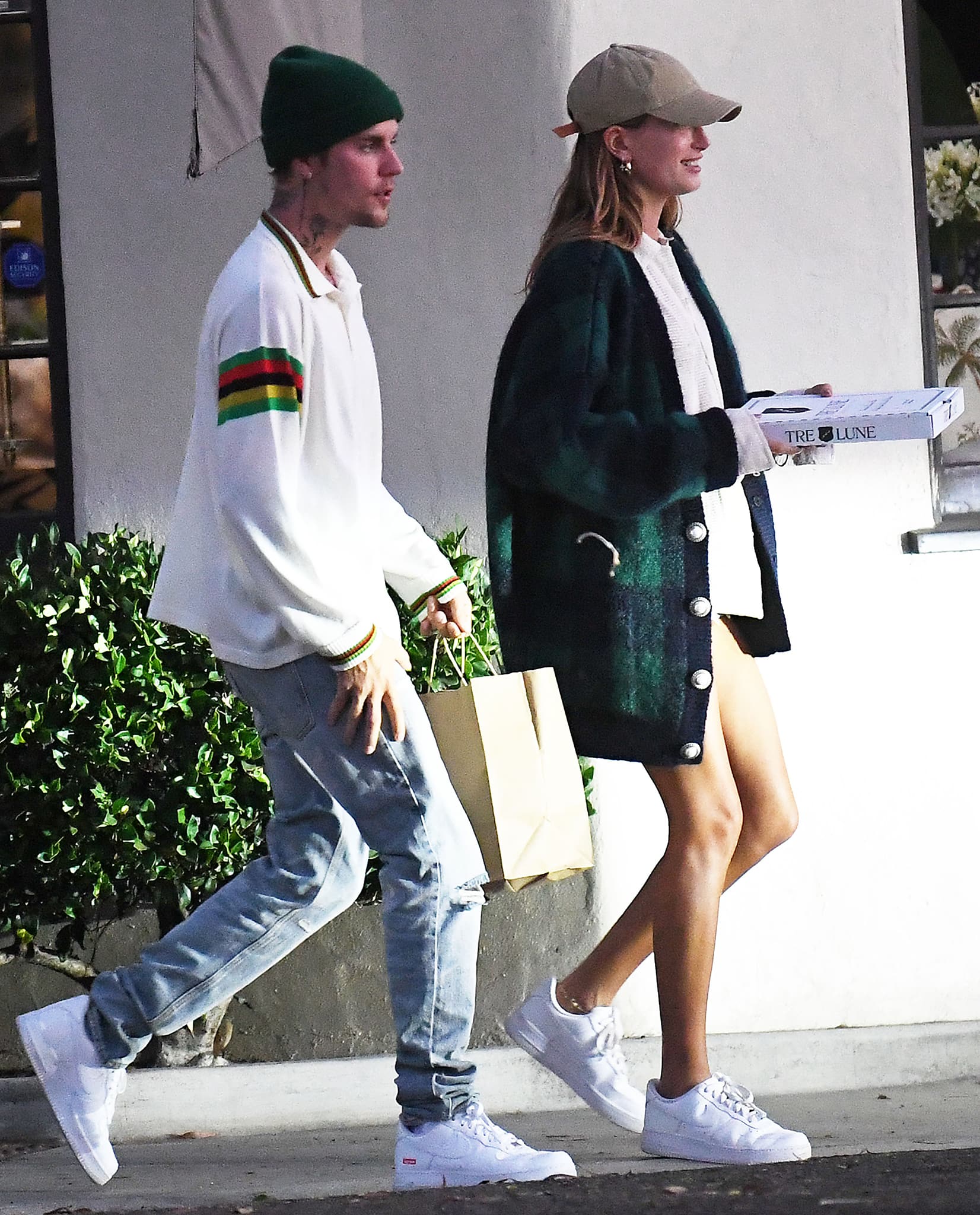 Hailey Bieber wearing white Nike Air Force 1 sneakers with EB Denim shorts and a Bode shirt