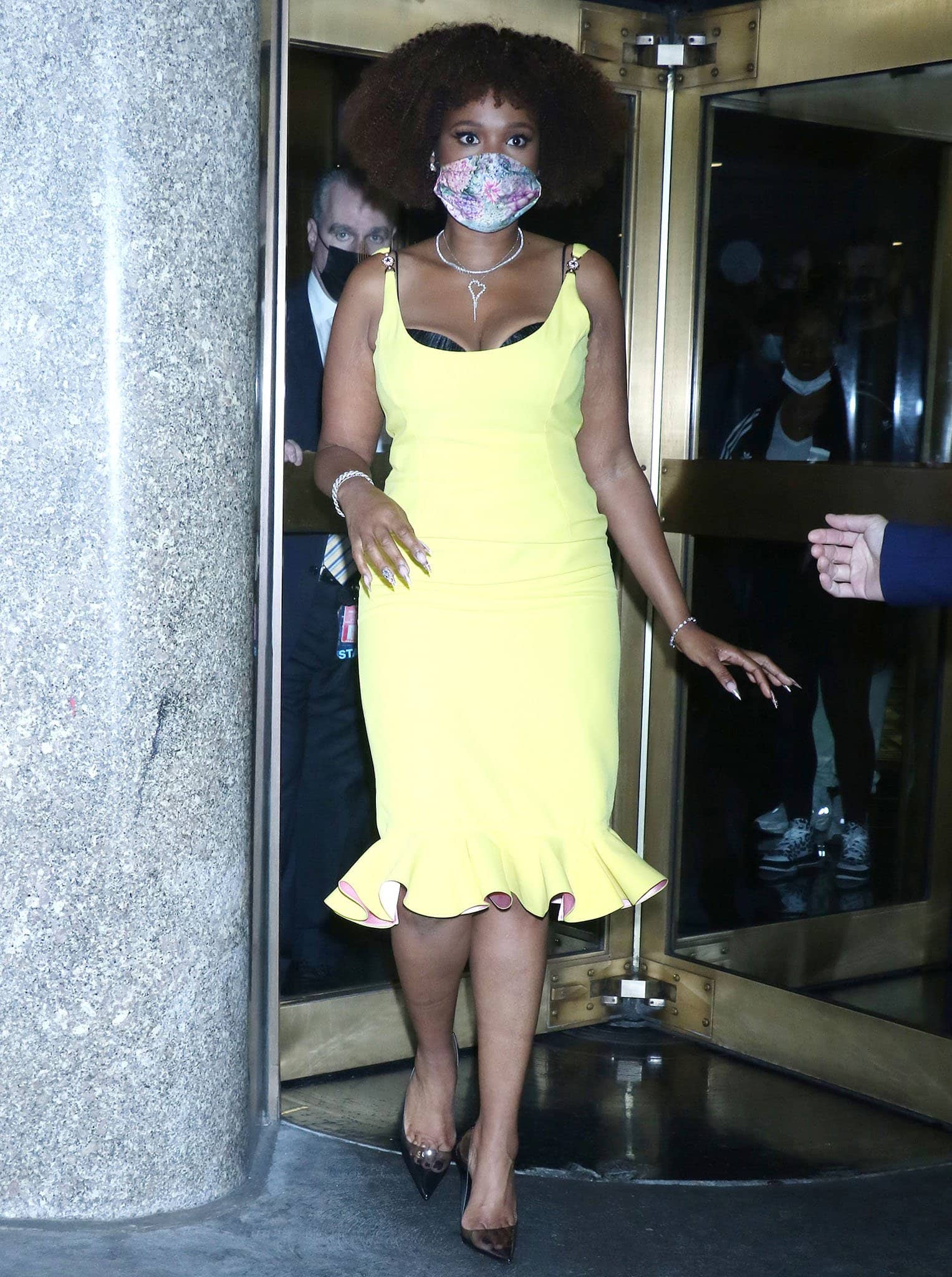 Jennifer Hudson radiates confidence in a figure-hugging yellow Versace Spring 2021 midi dress, styled with pointed-toe PVC pumps, layered jewelry, and a chic floral mask