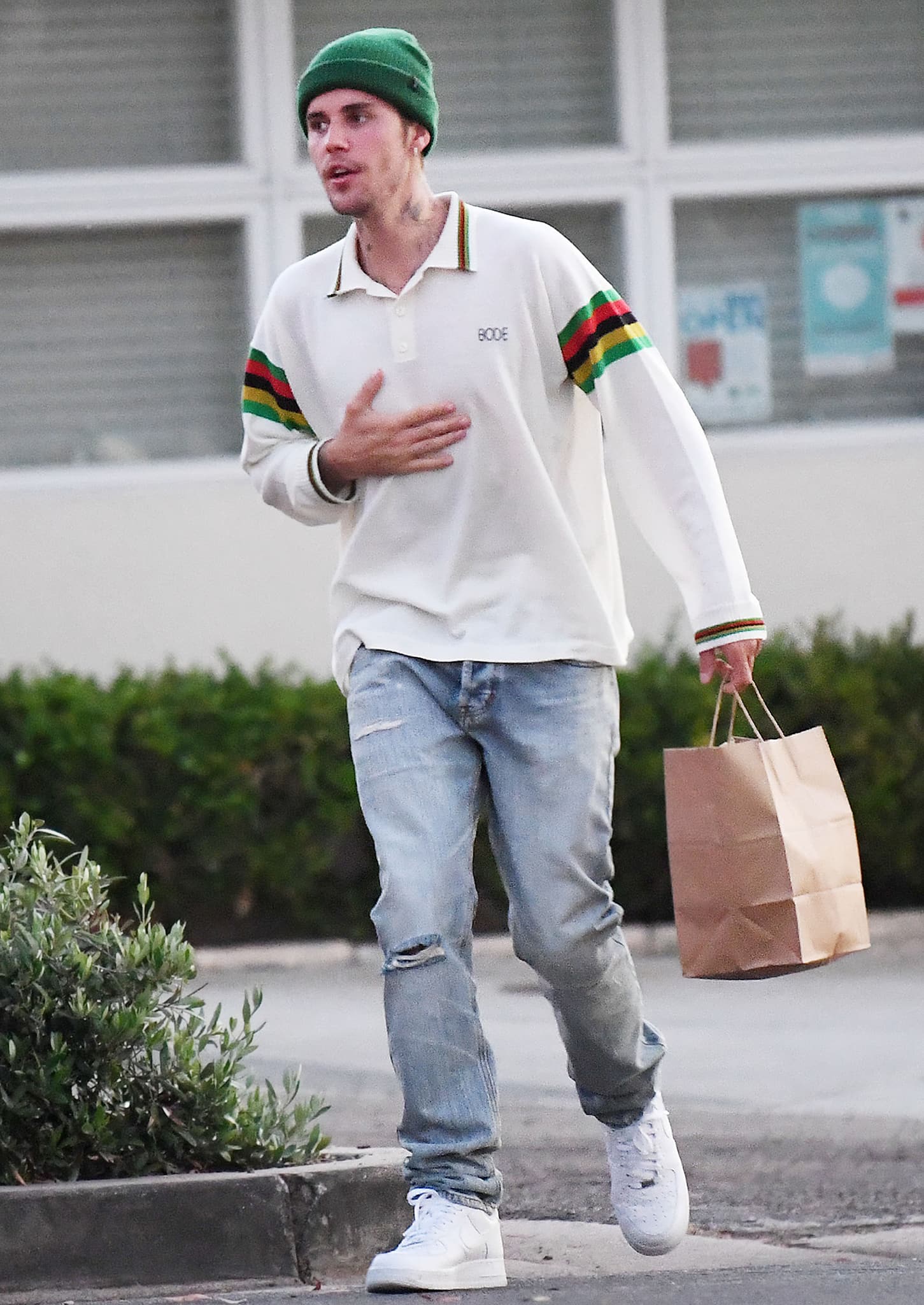 Justin Bieber wearing white Nike Air Force 1 Low sneakers with ripped jeans and a Drew House polo