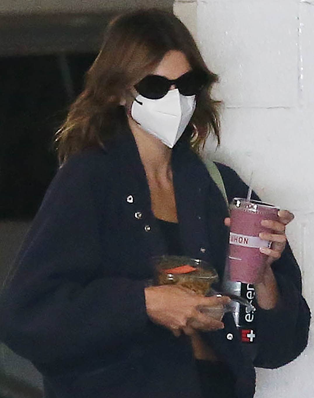Kaia Gerber keeps her look understated with sleek Celine sunglasses and a white face mask, letting her effortless, post-workout style speak for itself