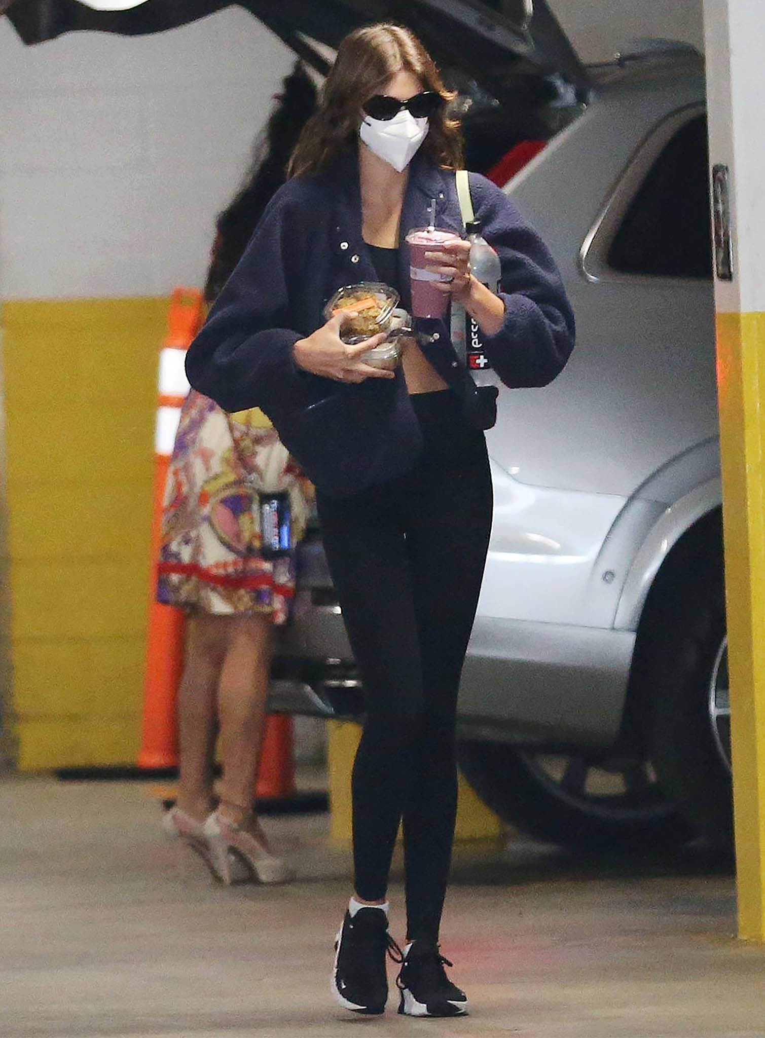 Kaia Gerber keeps her post-workout look sleek and functional in black leggings and a cropped layer, grounding the outfit with supportive Nike trainers that balance performance and off-duty style