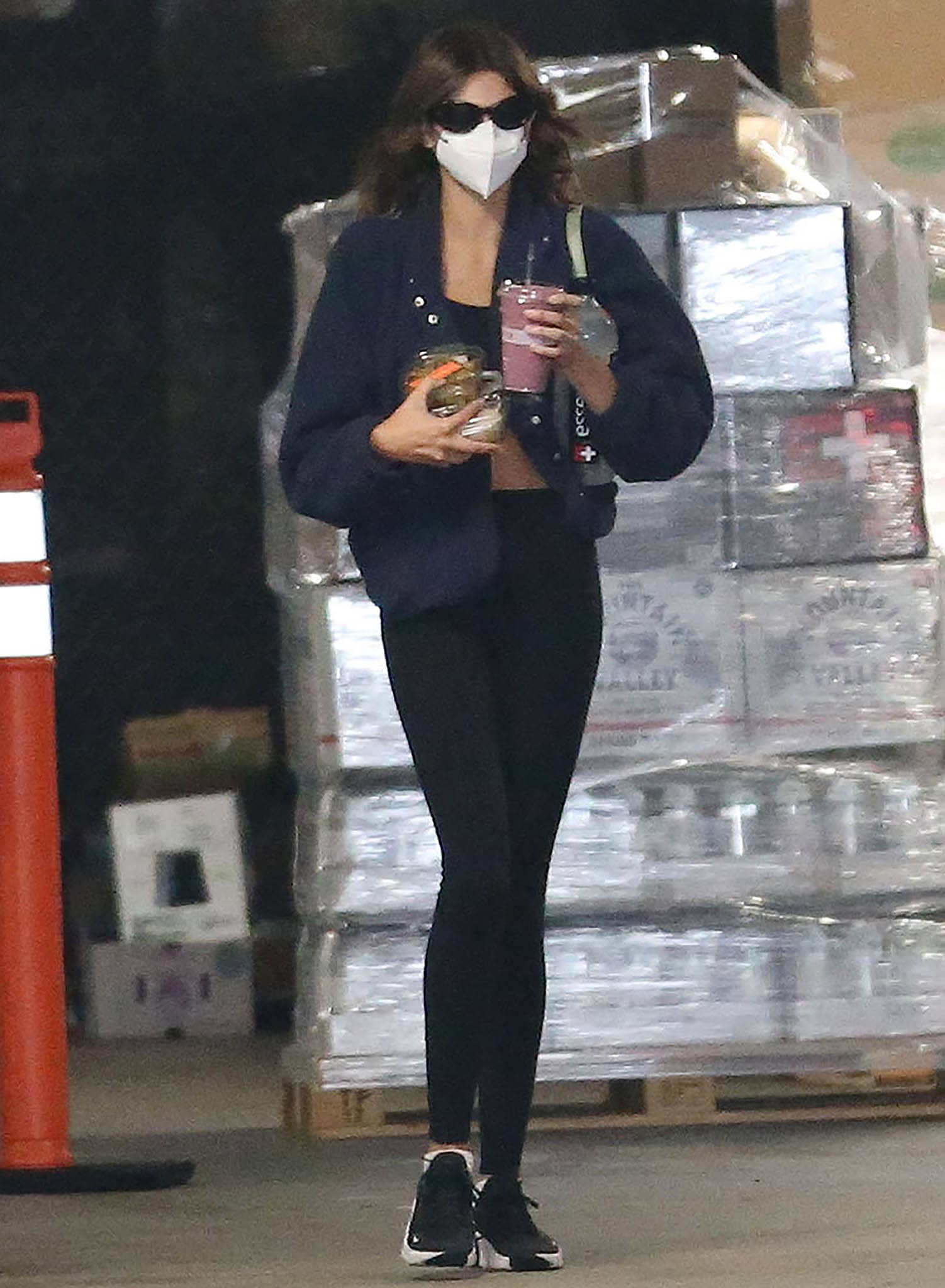 Kaia Gerber steps out in West Hollywood with a smoothie in hand, pairing sleek black leggings and a cropped layer with grounded Nike trainers that keep her post-workout look effortless and functional