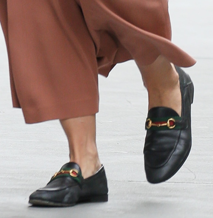 Katie Holmes finishes her relaxed tailoring with black Gucci Brixton loafers, distinguished by the house's signature green-and-red Web stripe and gold horsebit hardware