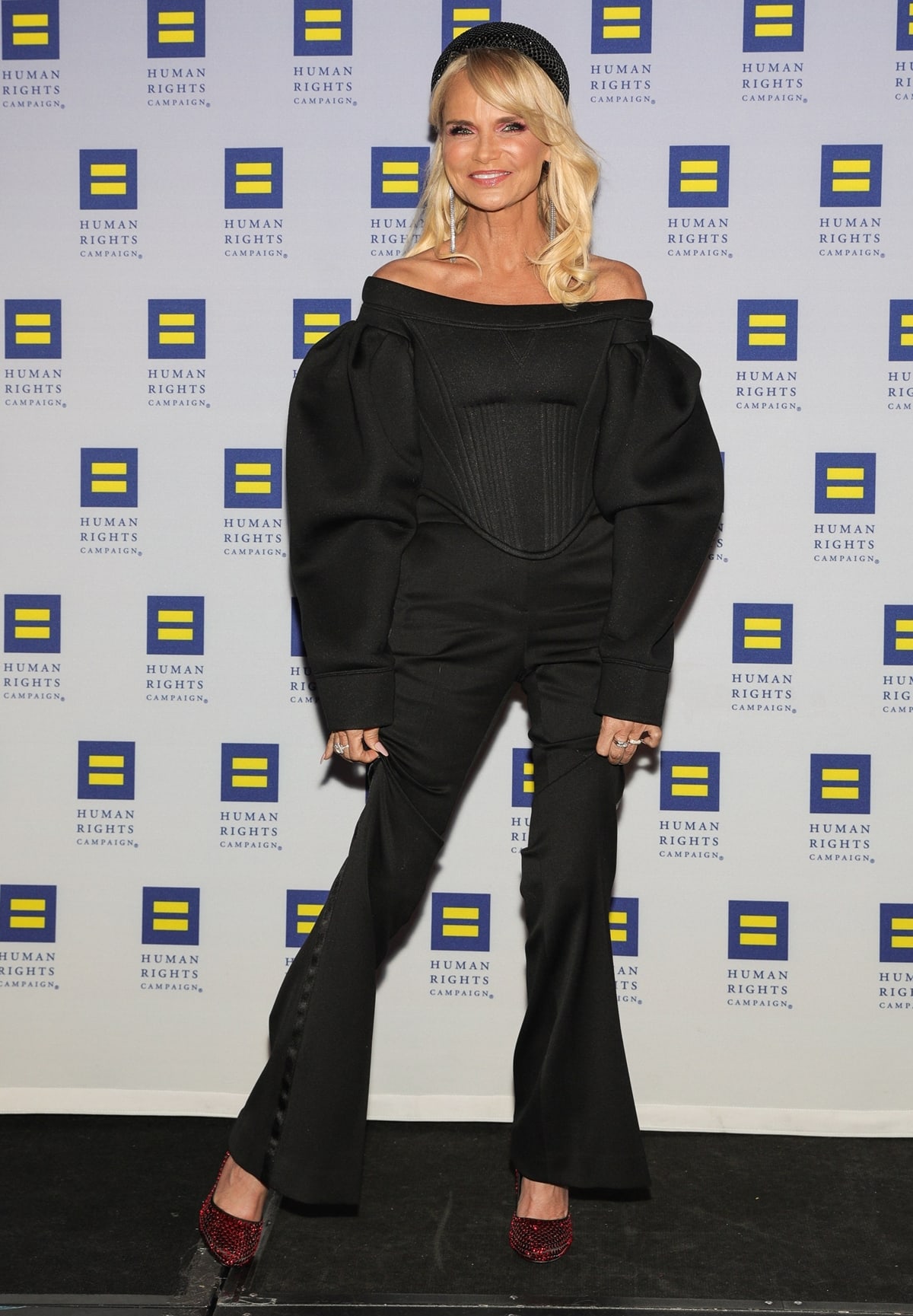 Event honoree Kristin Chenoweth attended the Human Rights Campaign's 19th Annual Greater New York Gala on February 1, 2020, at the Marriott Marquis Hotel in New York City, where she showcased a striking black outfit featuring an off-the-shoulder top with dramatic puff sleeves and a structured bodice, paired with sleek trousers and sparkling red heels