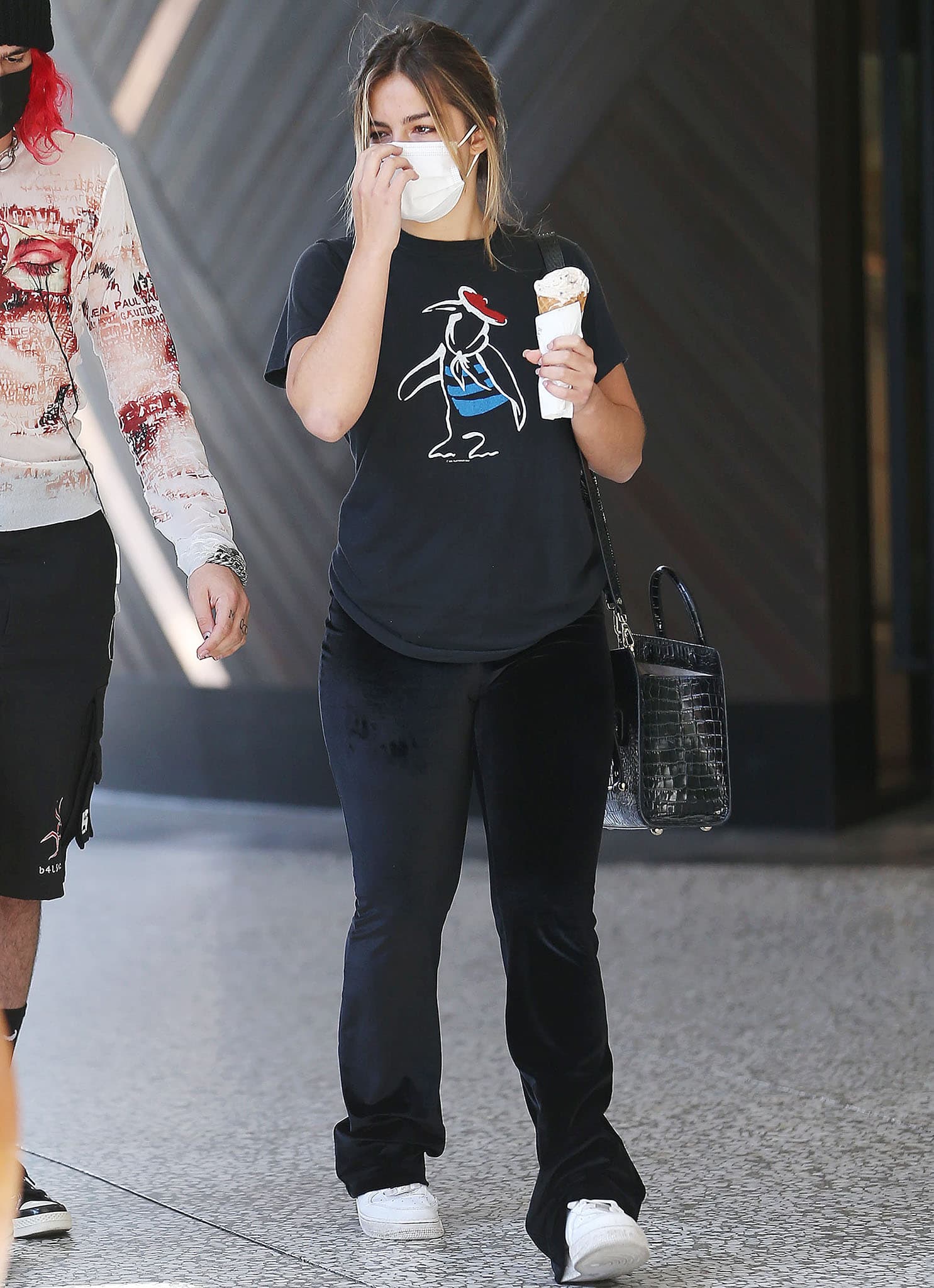 Addison Rae pairs a vintage-inspired Fleetwood Mac 1982 Mirage Tour tee with black Fila velvet pants, grounding the relaxed look with crisp white Nike Air Force 1 sneakers that add a clean, street-ready finish