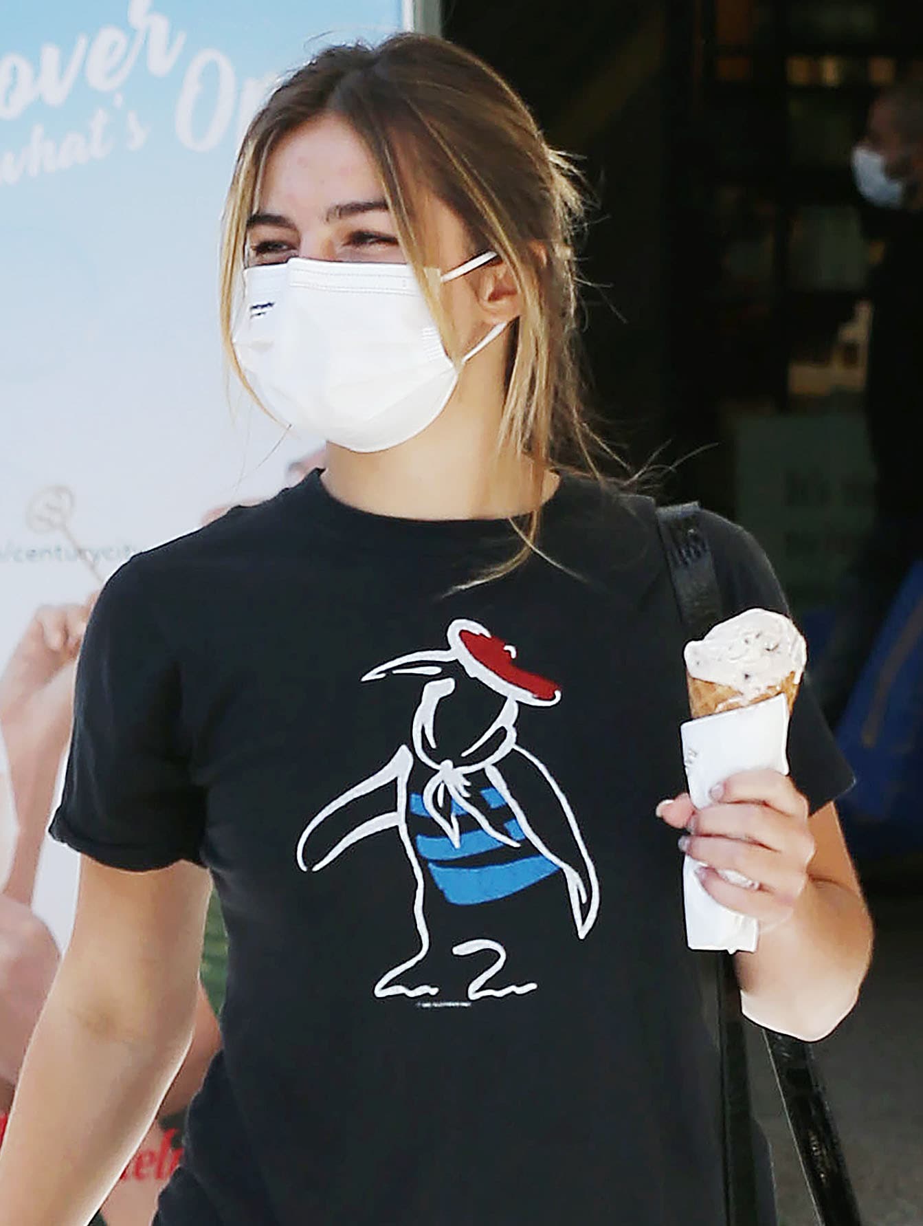Addison Rae wears her hair in a messy bun and stays safe with a white face mask
