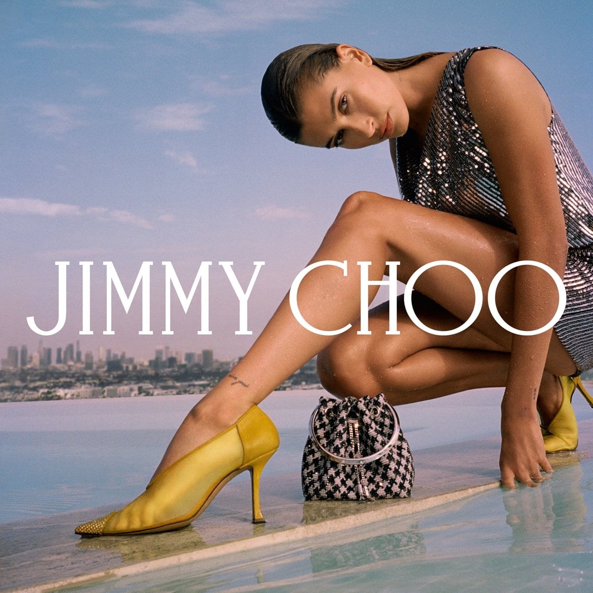 Hailey Bieber in yellow mesh and suede Nicole pumps shows off Jimmy Choo's latte and black satin star houndstooth print Bon Bon mini bag