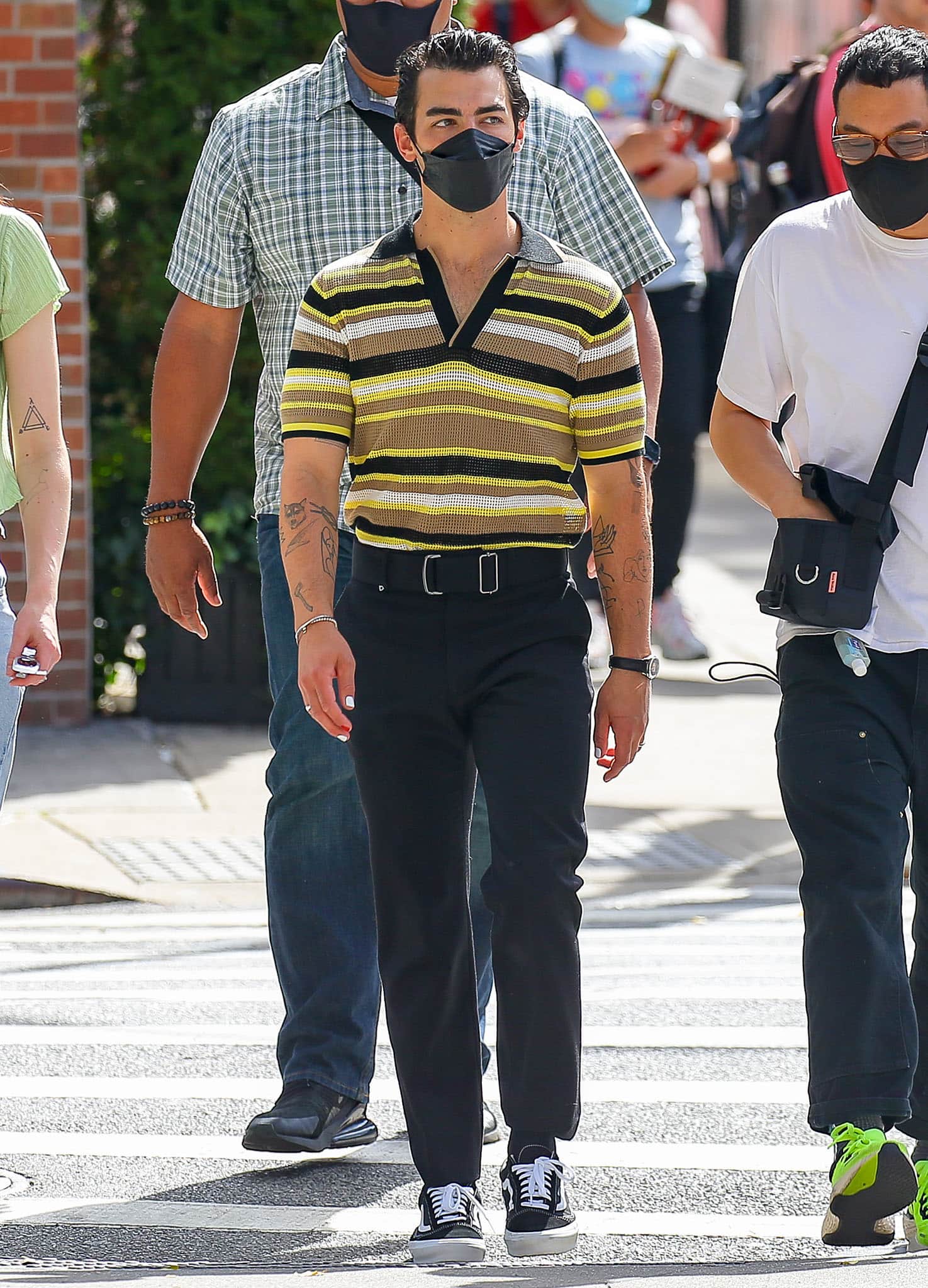 Joe Jonas coordinates with his wife in a throwback waffle knit striped top with black trousers and Vans sneakers