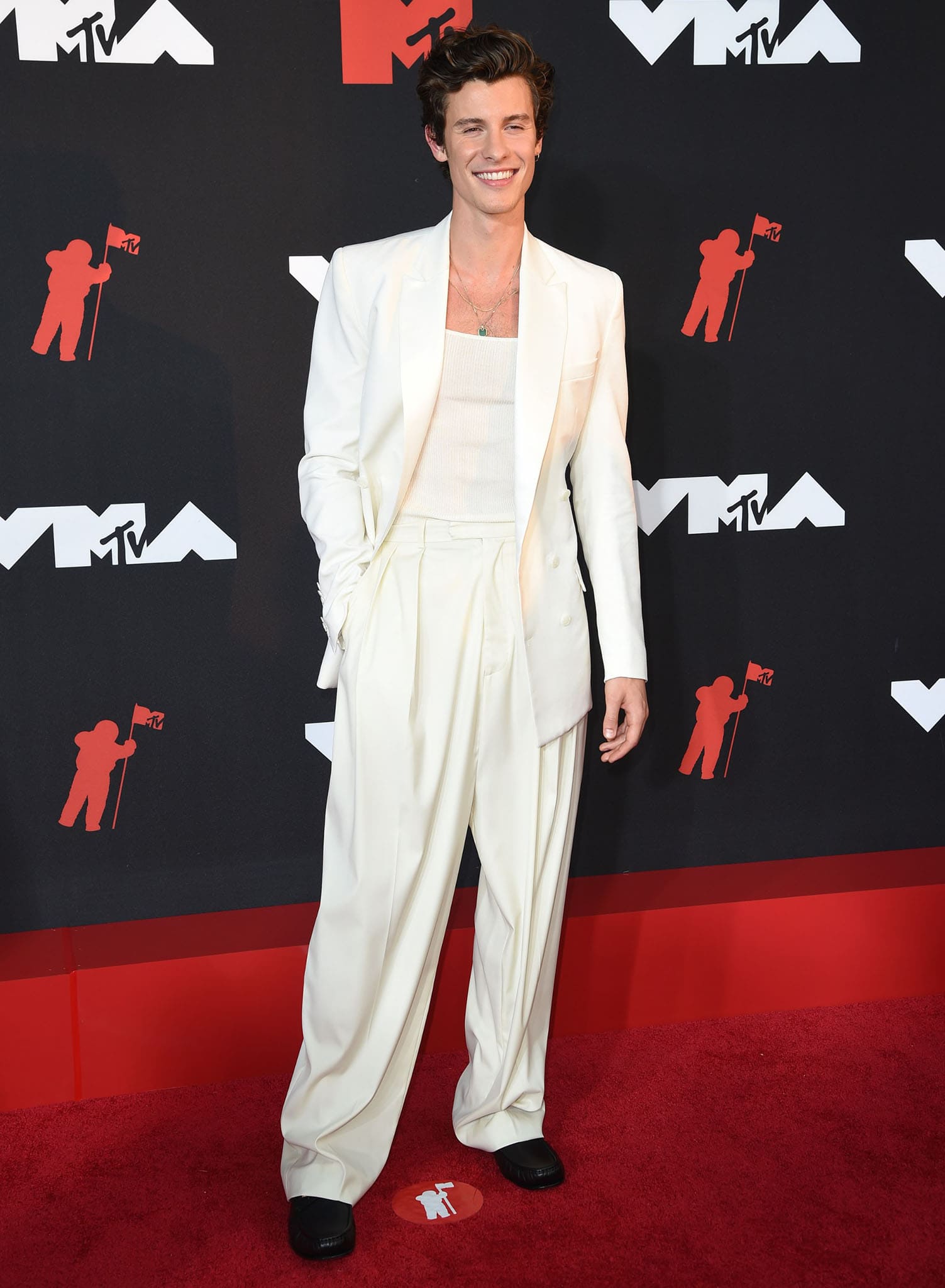 Shawn Mendes embraces minimalist elegance in a ribbed tank, crisp white blazer, and pleated cream trousers at the 2021 MTV VMAs