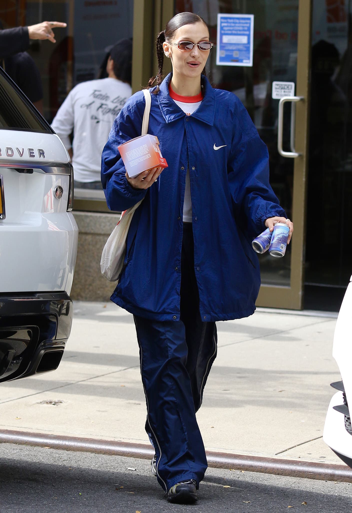 An oversized Nike jacket and pooling track pants exaggerate the proportions of Bella Hadid’s sporty look, while her low-profile ASICS sneakers keep the silhouette grounded