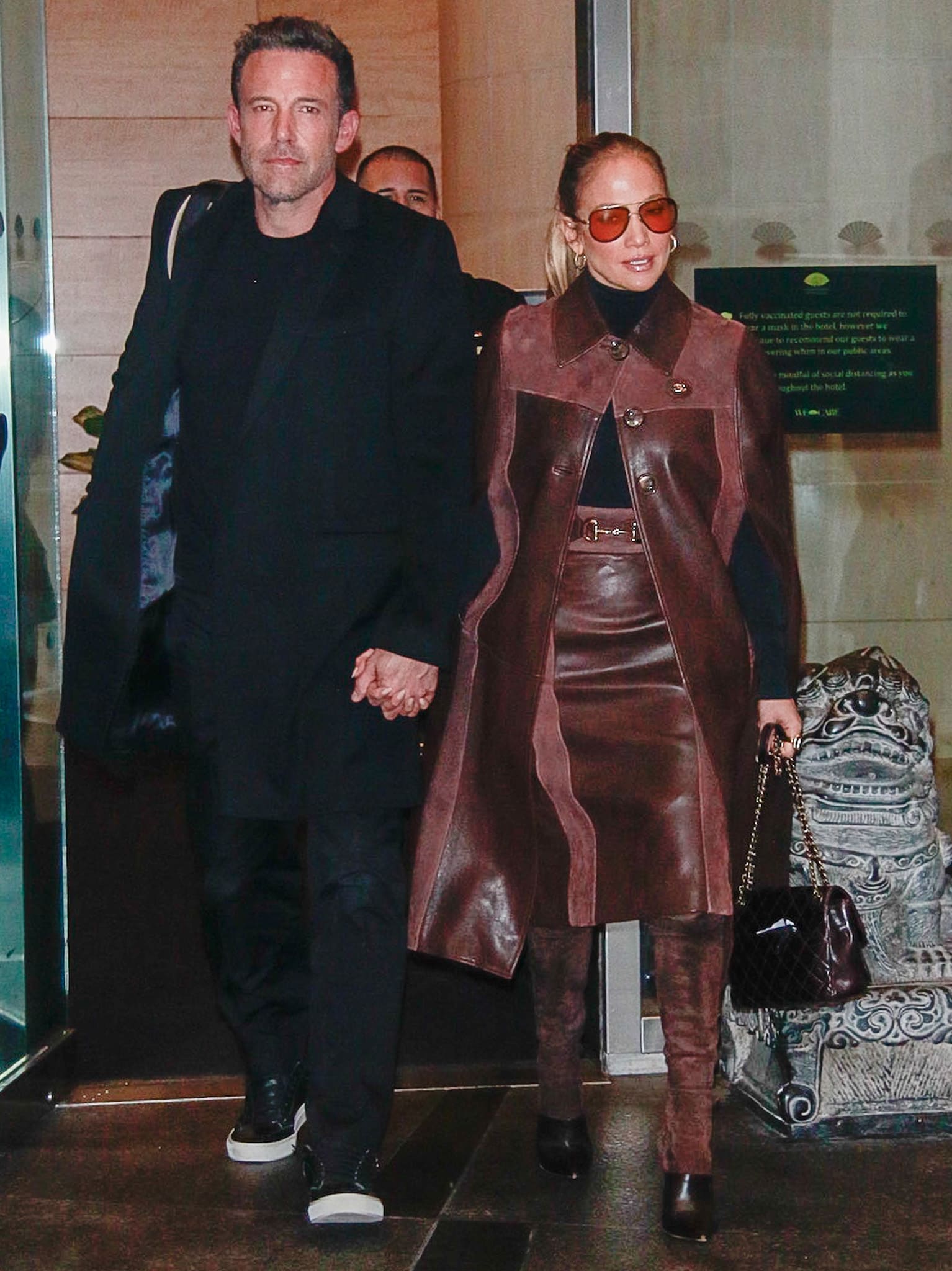 Jennifer Lopez elevates her monochromatic Gucci leather ensemble with Balmain "Amazon" thigh-high boots, while Ben Affleck keeps his all-black look grounded with minimalist black leather dress sneakers
