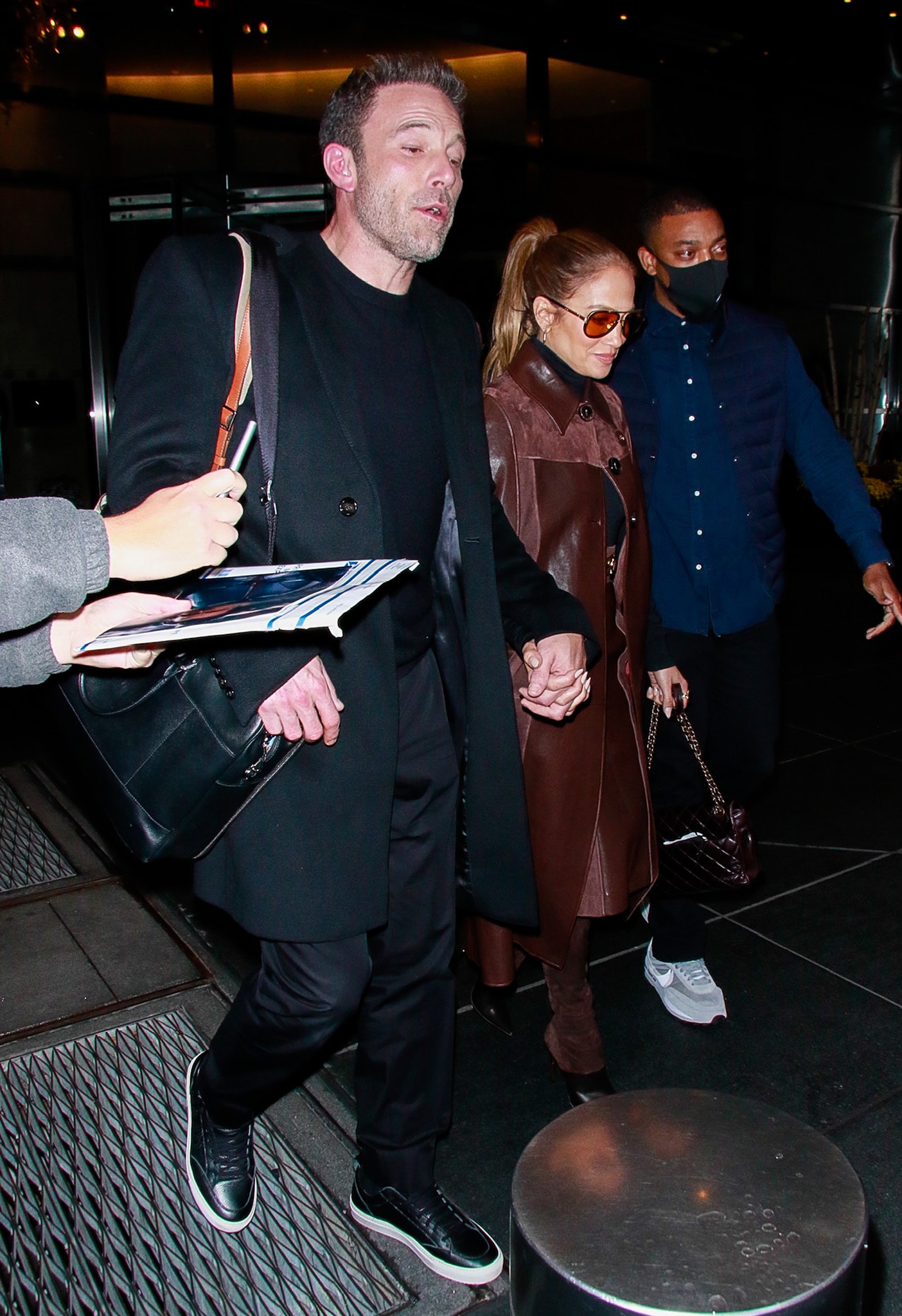 Ben Affleck's clean black leather sneakers provide a smart-casual contrast to Jennifer Lopez's dramatic Balmain thigh-high boots, highlighting the couple's mix of understated menswear and statement luxury fashion