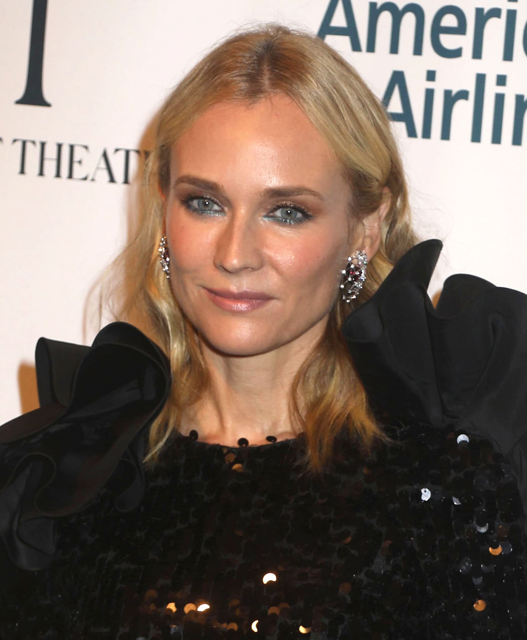 A closer look at Diane Kruger’s soft waves, bronze smoky eye, and crystal drop earrings, subtly contrasted with a teal-lined lower lash
