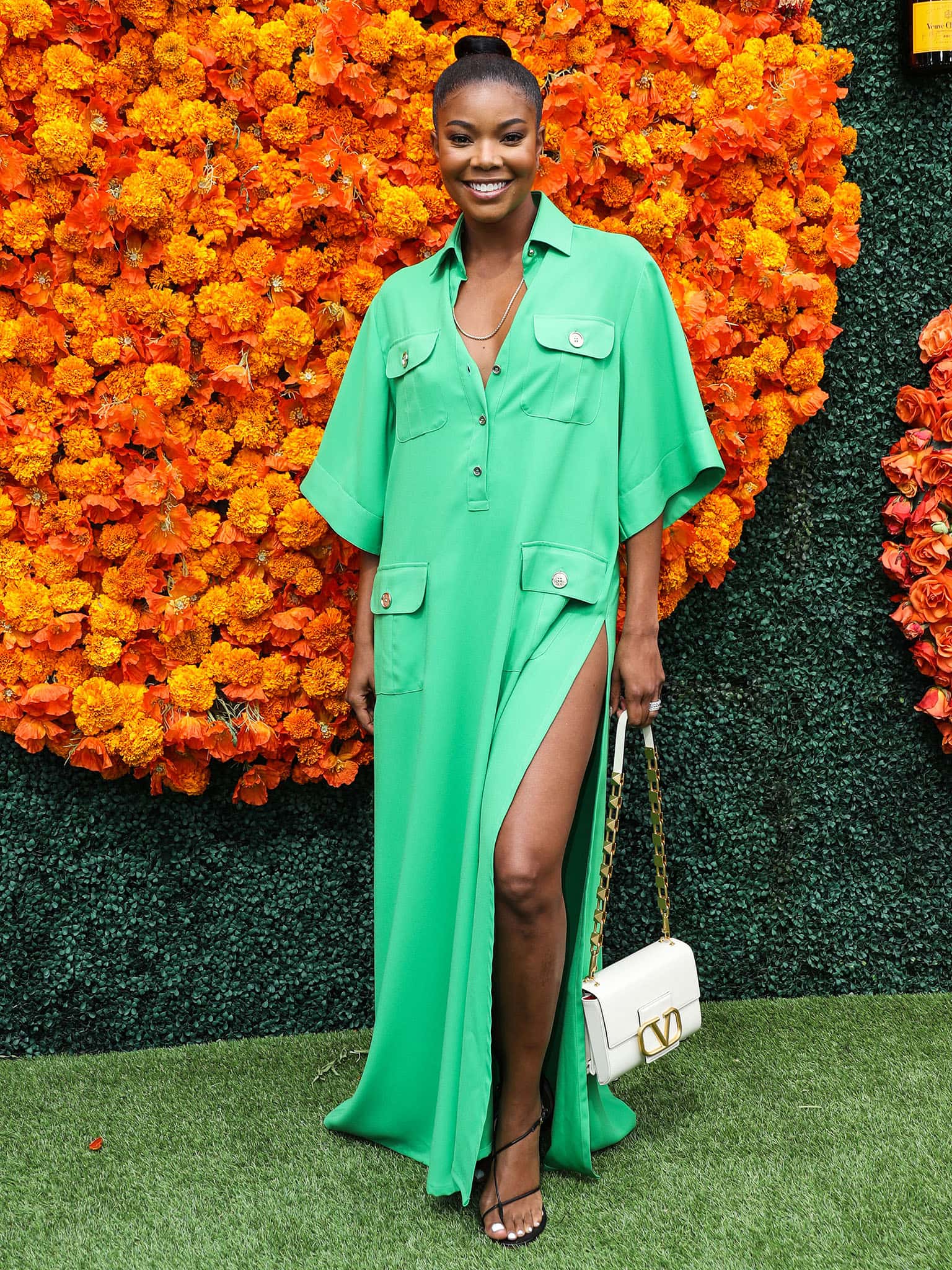 Radiating confidence, Gabrielle Union beams in a vibrant green Elie Saab maxi shirtdress, accessorized with gold jewelry and a sleek bubble ponytail at the 2021 Veuve Clicquot Polo Classic in Los Angeles