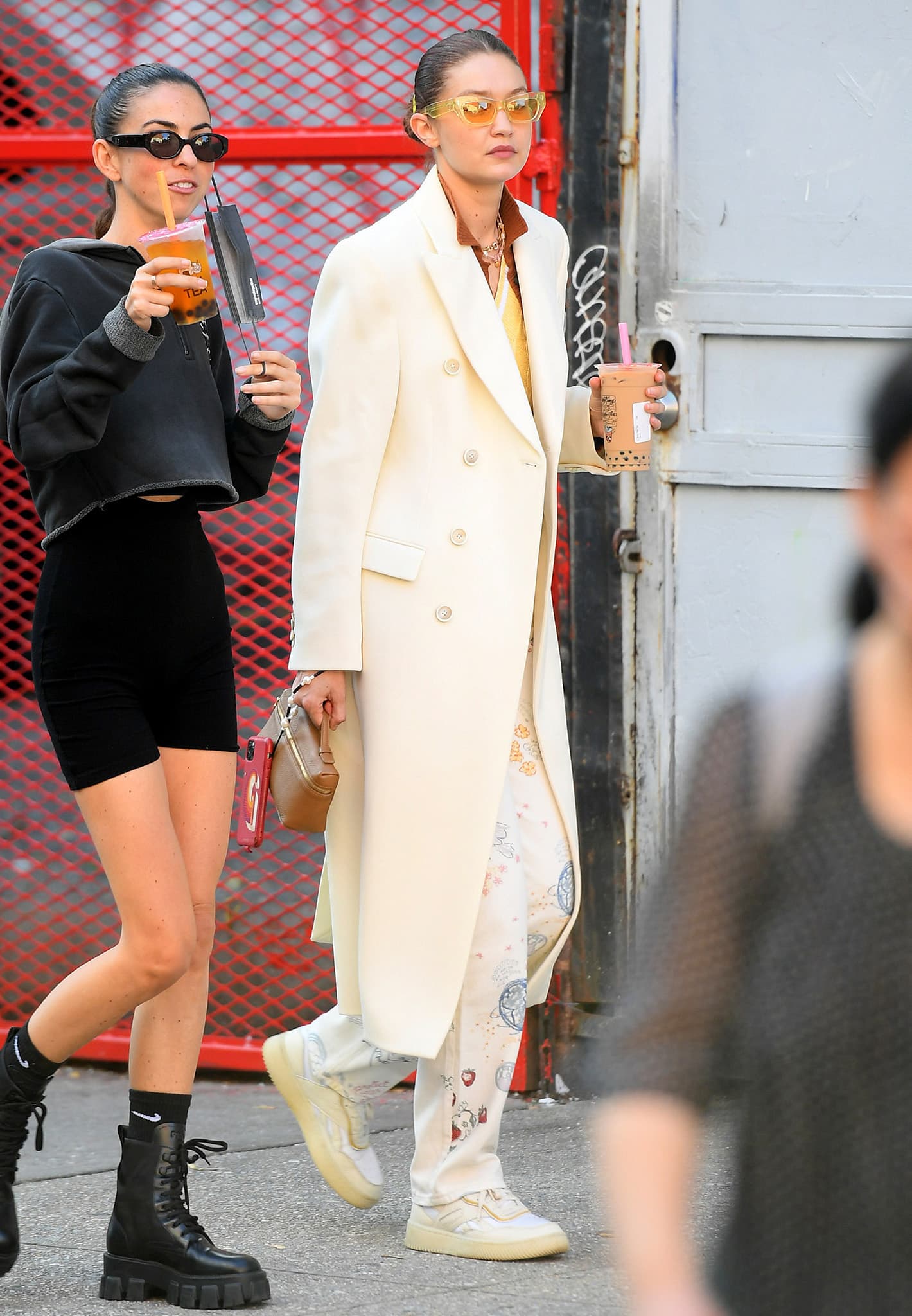 Gigi Hadid pairs a cream Wardrobe.NYC coat and printed Reformation trousers with Reebok x Victoria Beckham Dual Court II trainers while grabbing boba tea with a friend in New York City on October 11, 2021.