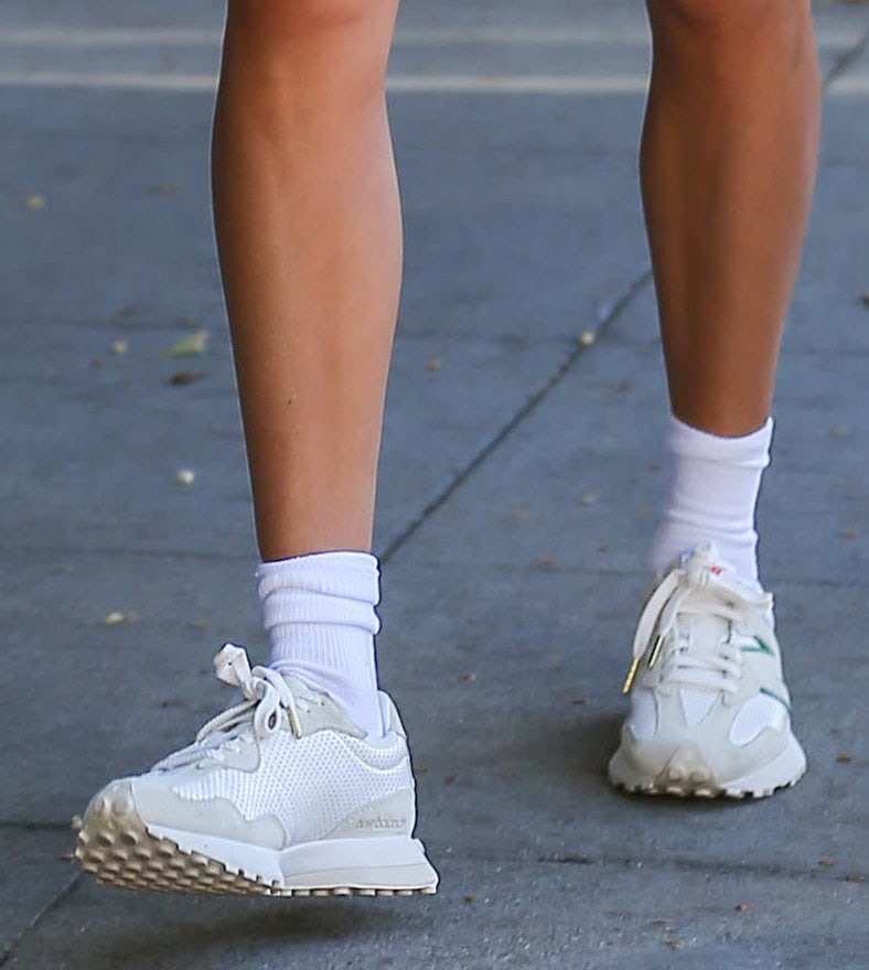 Hailey Bieber grounded her sporty off-duty look with Casablanca x New Balance 327 sneakers, pairing the retro-inspired silhouette’s perforated leather panels, oversized “N” logo, and trail-style outsole with crisp white crew socks for a clean 1970s runner revival feel