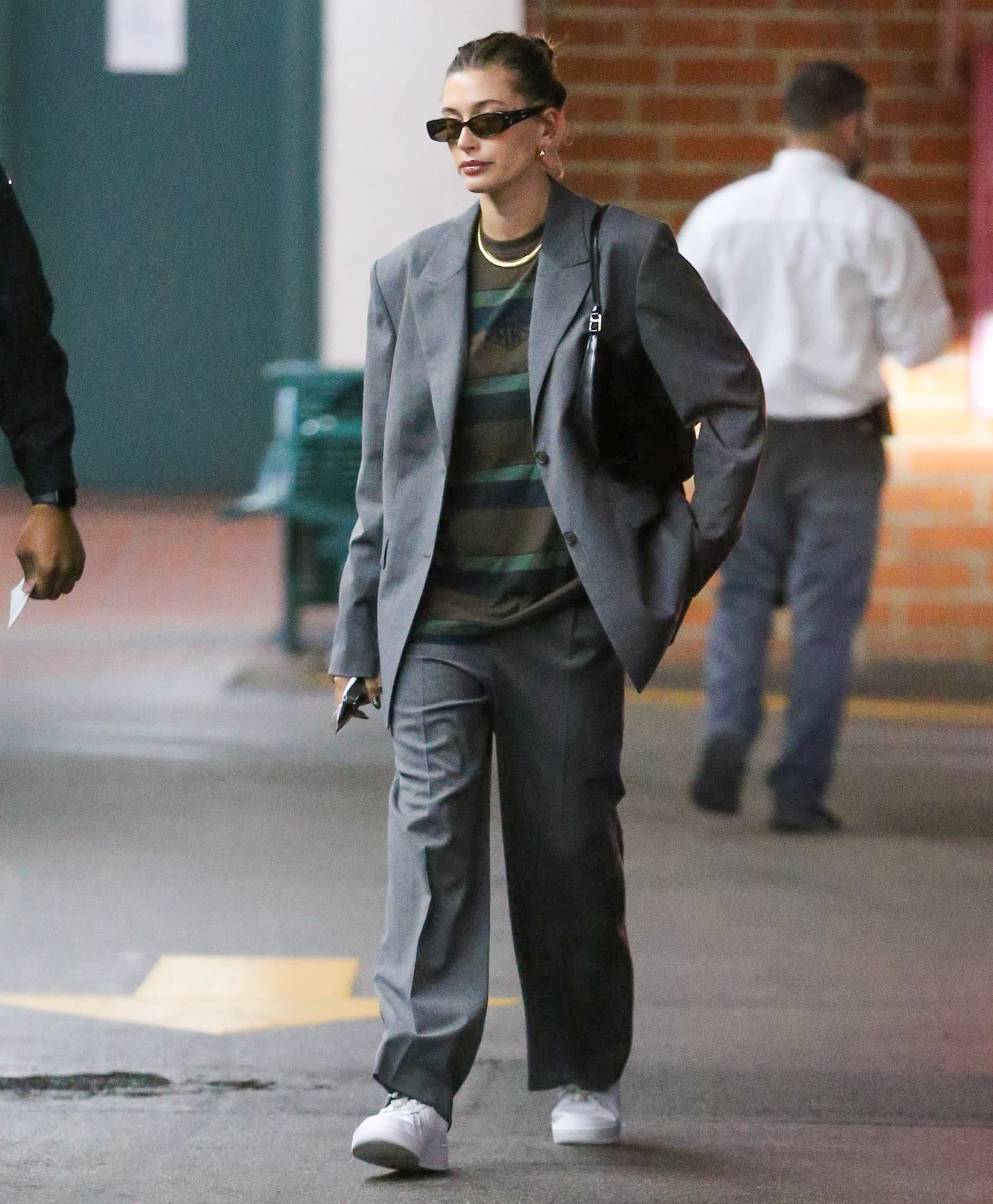 Hailey Bieber wears a loose-fitting Han Kjøbenhavn gray suit with a striped sweater underneath