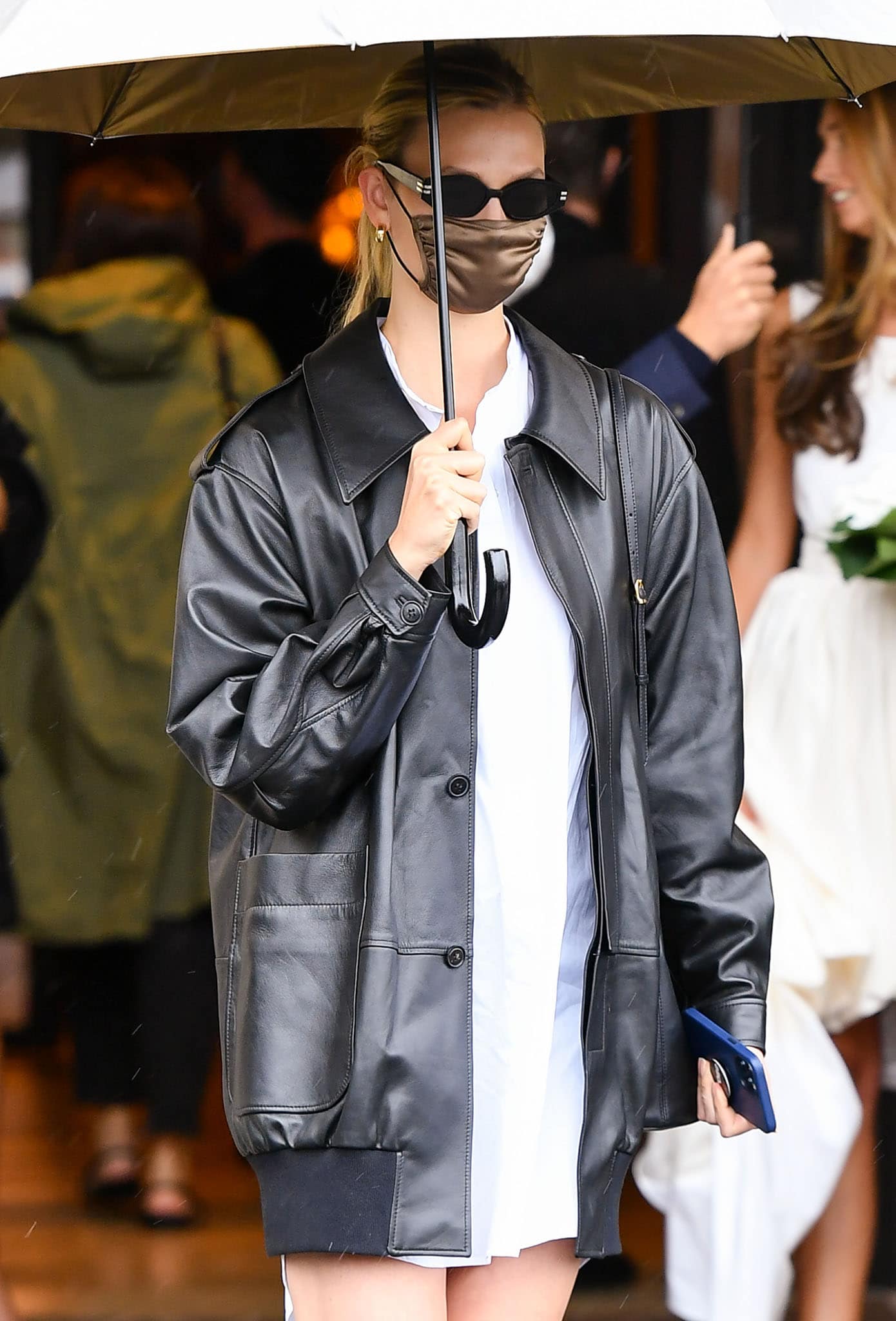 Karlie Kloss keeps things low-key with a pair of black sunglasses and a bronze face mask