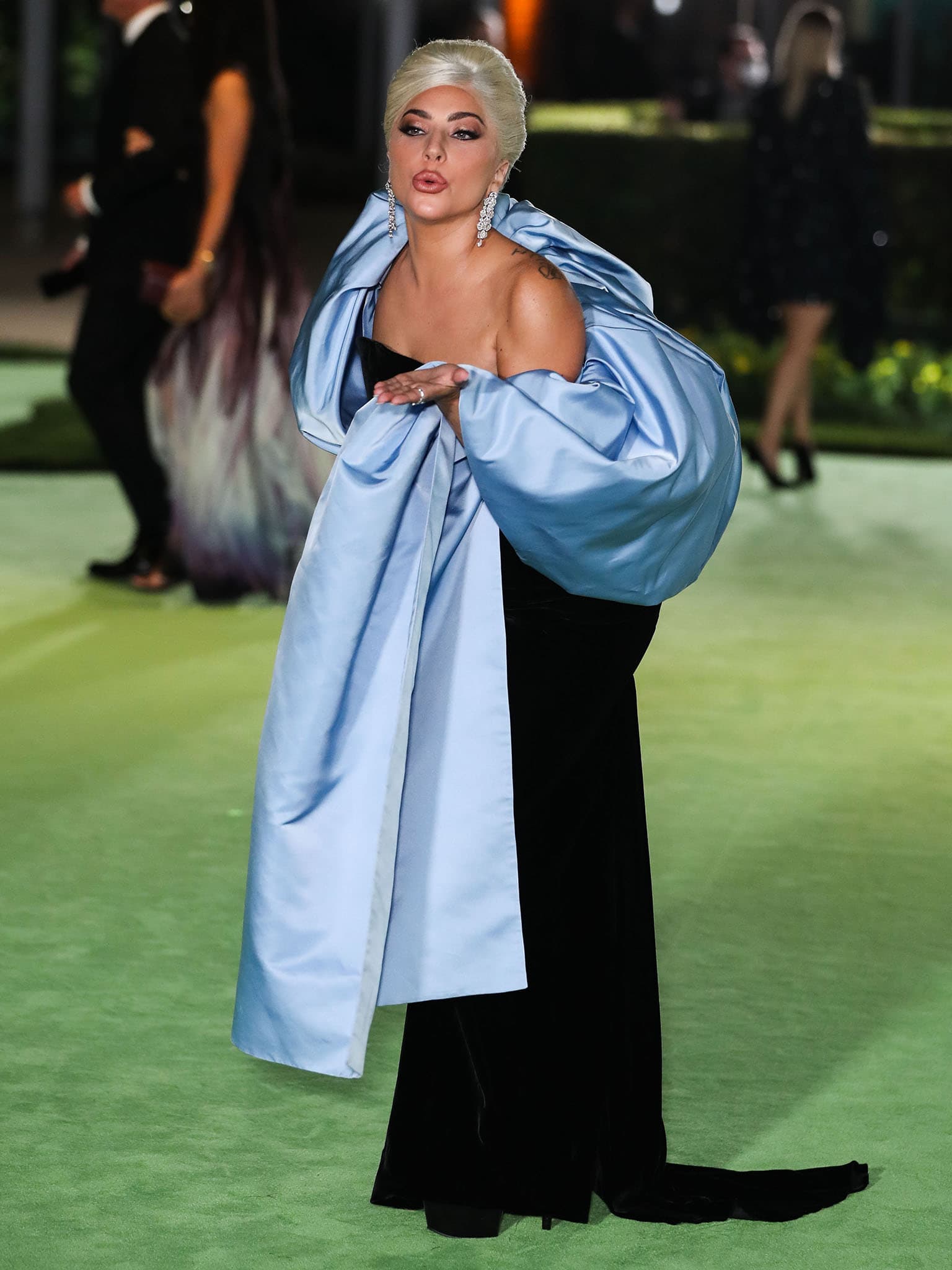 Lady Gaga lets Schiaparelli’s sculptural powder blue satin stole take center stage as she poses on the green carpet at the Academy Museum Opening Gala