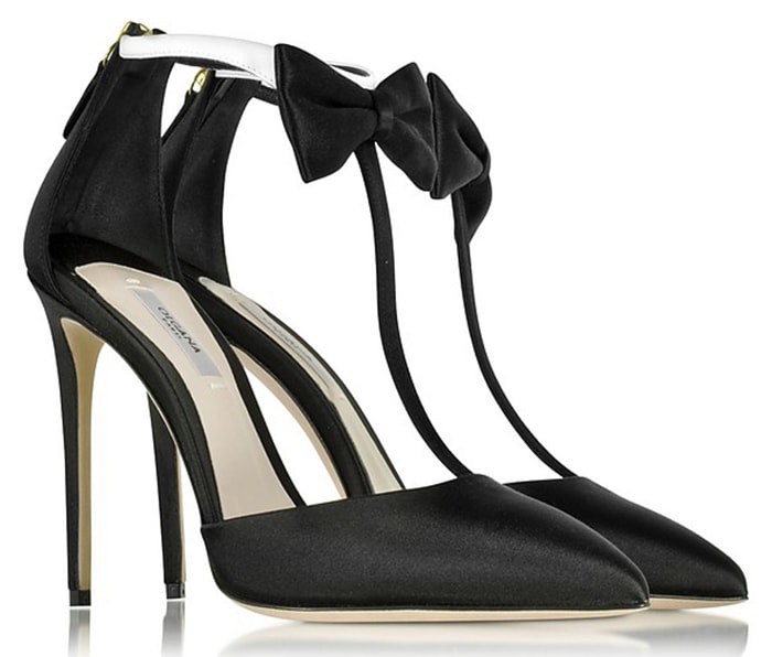 The Olgana Paris “La Garçonne” pumps combine black satin with a contrasting white ankle strap and delicate bow detail, set on a slender high heel