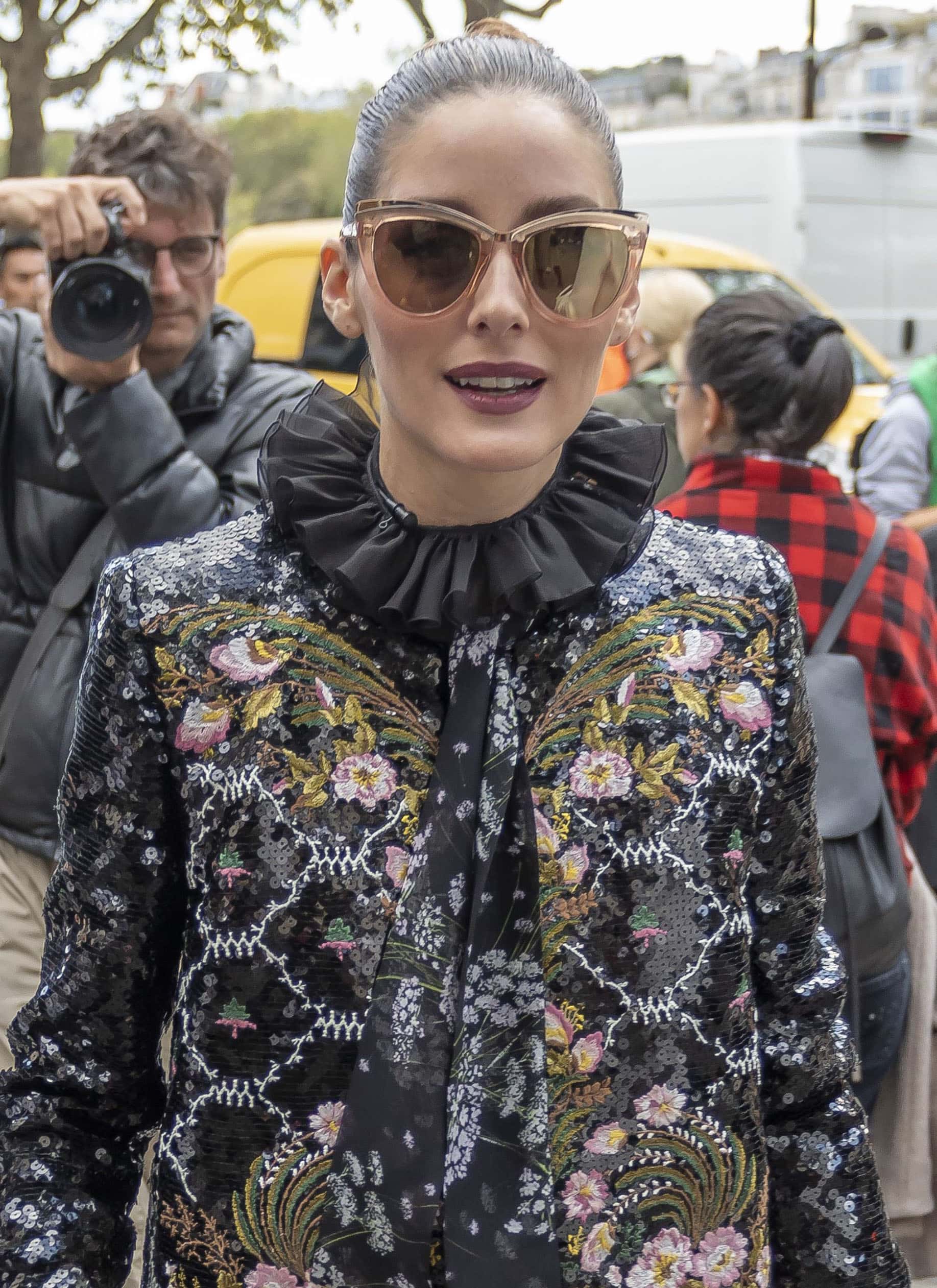 Olivia Palermo ties her hair into a sleek bun and wears dark mauve lipstick