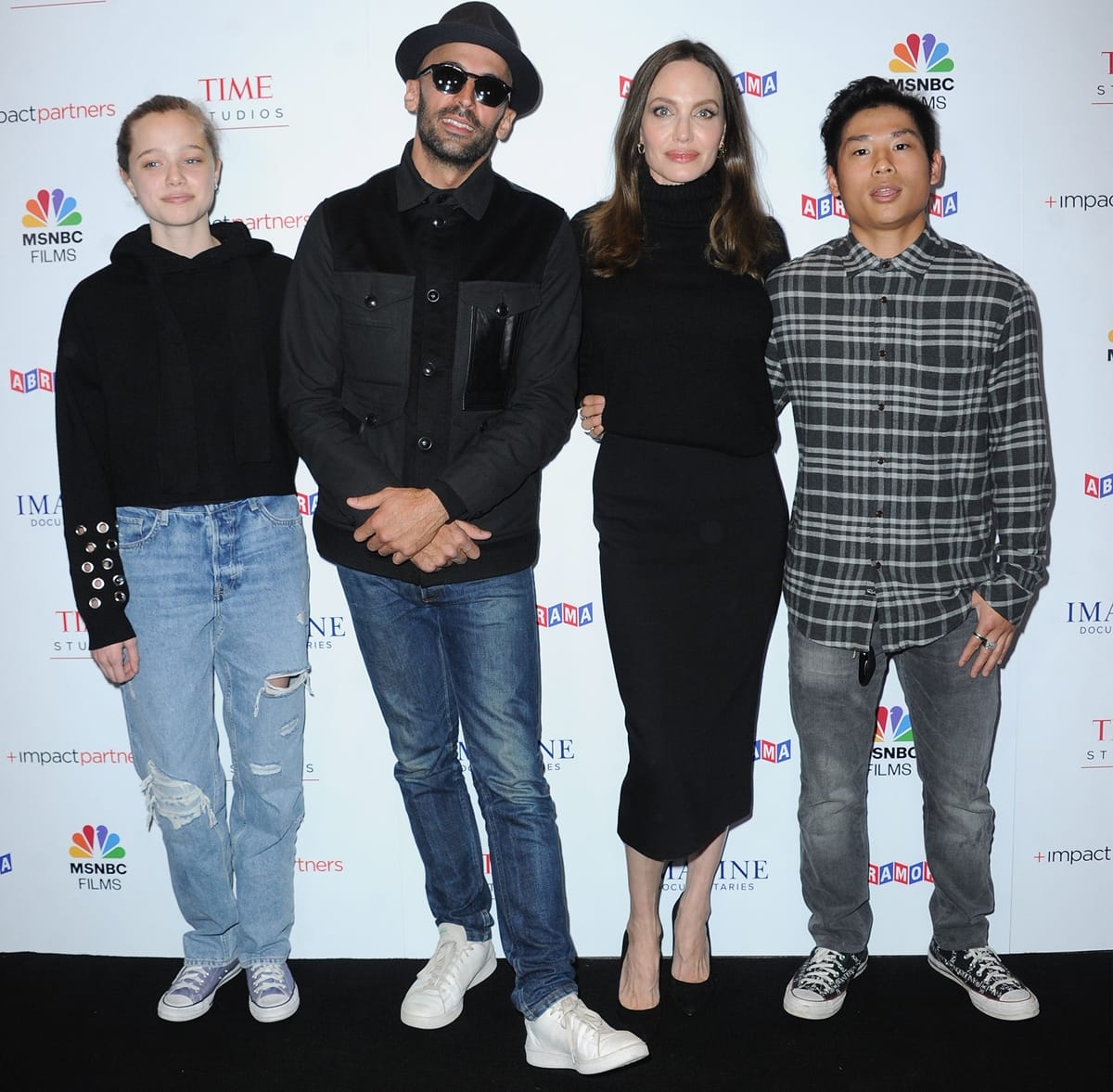 Angelina Jolie attends the Los Angeles premiere of Paper Glue: A JR Project with street artist JR and her children Shiloh and Pax Jolie-Pitt — balancing relaxed and refined style as Shiloh pairs ripped jeans and Converse sneakers with Jolie’s sleek black midi dress
