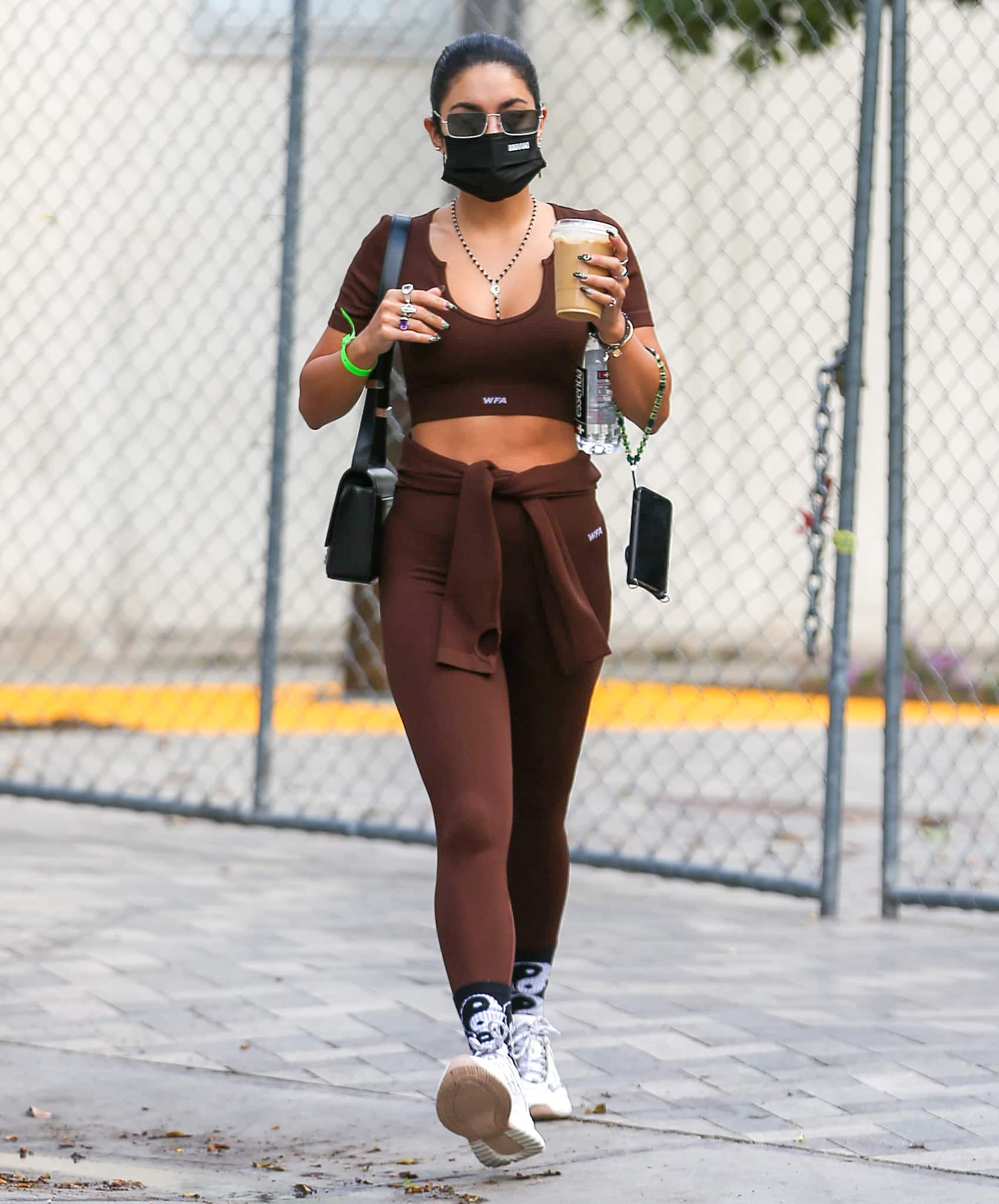 Vanessa Hudgens leans into sleek, monochrome athleisure, finishing a chocolate-brown White Fox crop top and leggings with playful yin-yang socks and her go-to white Mercer Amsterdam “Jupiter” sneakers for an effortlessly cool post-workout stride