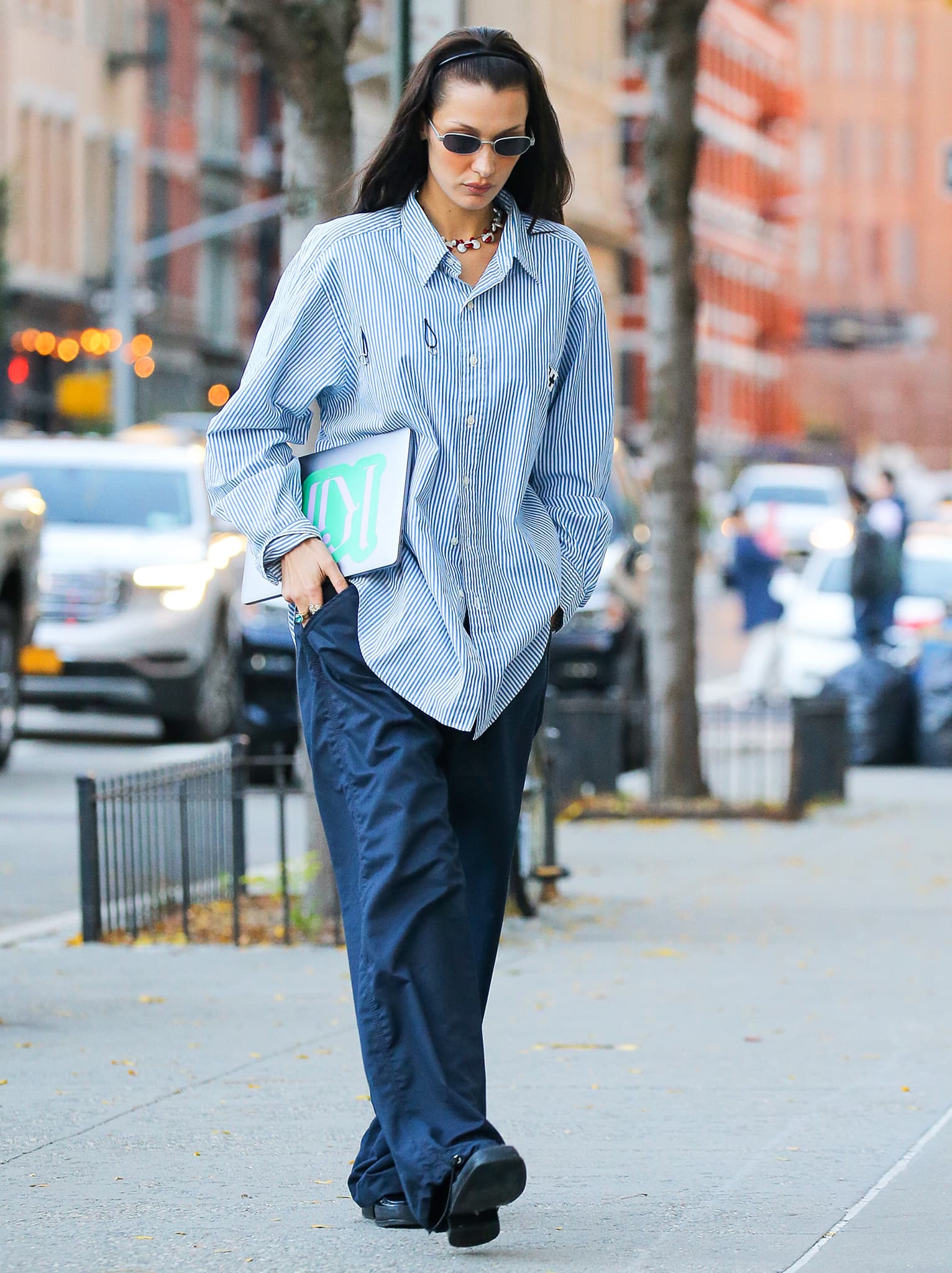 Bella Hadid leans into relaxed proportions in a billowing striped button-down and wide-leg trousers, letting her polished Prada loafers give the look a more structured finish