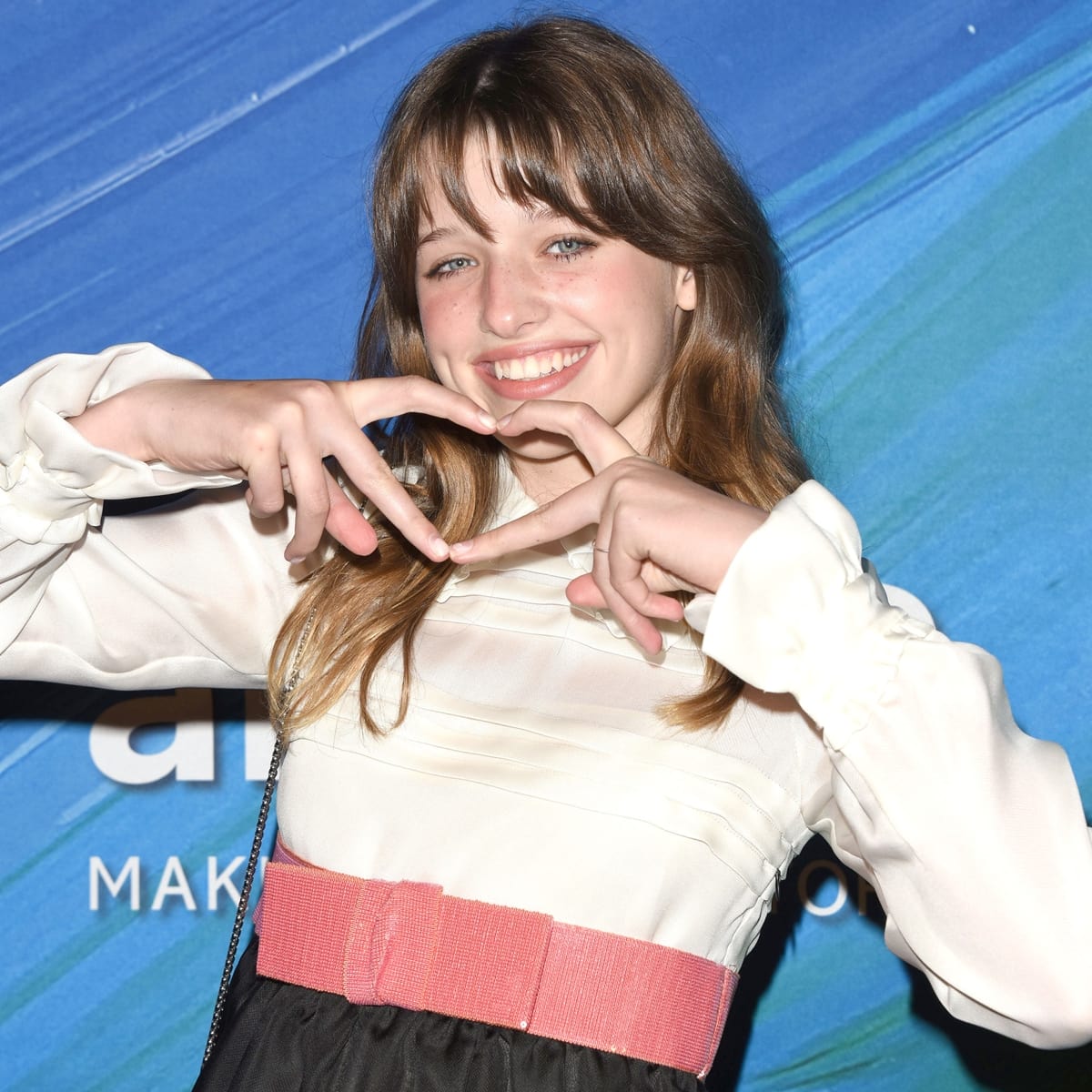 Ever Gabo Anderson flashes a heart sign with a radiant smile, showcasing her playful personality and youthful style