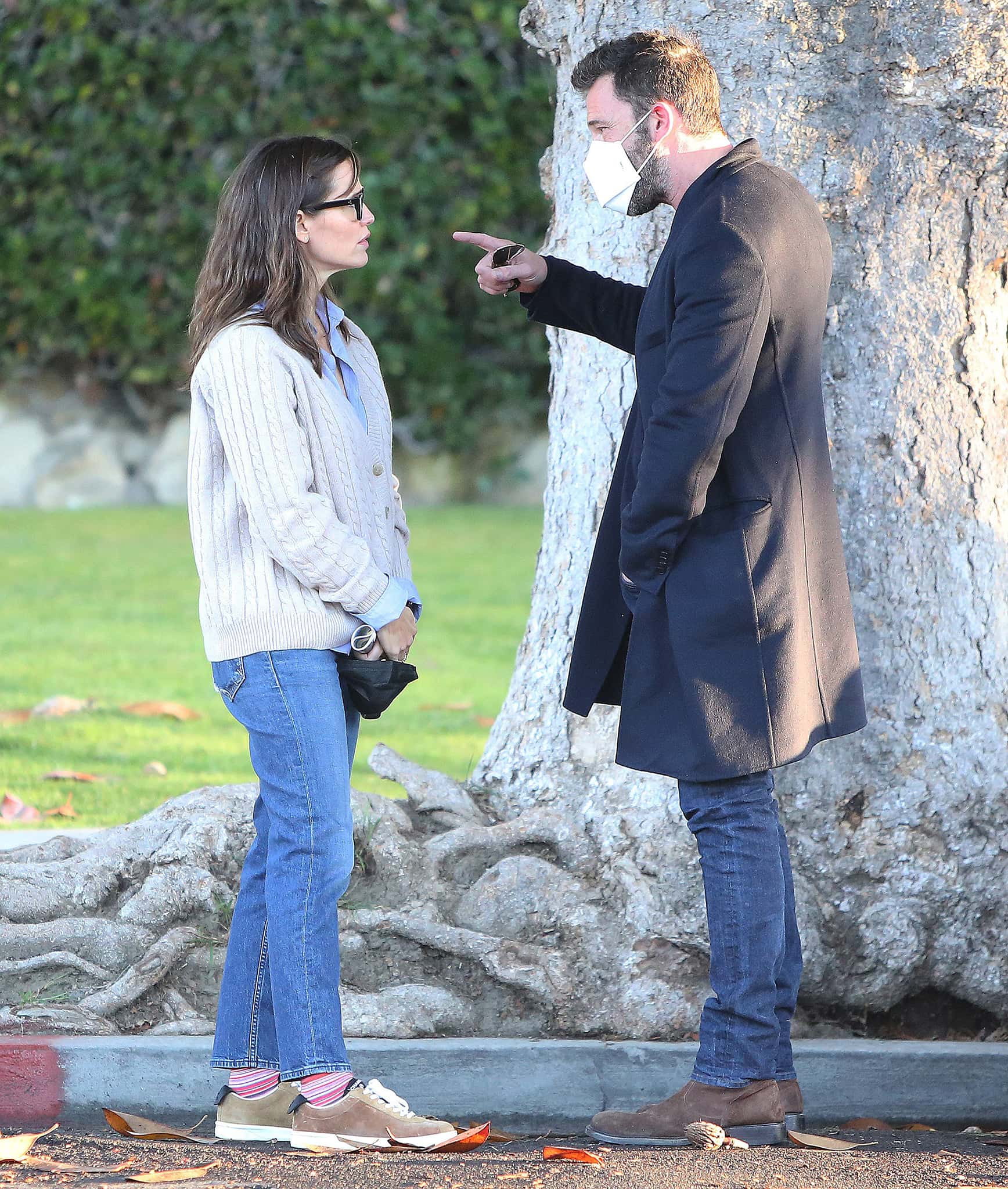 Jennifer Garner kept her off-duty look relaxed in flared jeans, striped socks, and neutral retro-inspired sneakers while chatting with Ben Affleck, who layered a dark overcoat over denim and suede Chelsea boots during an outing in Santa Monica on December 9, 2021