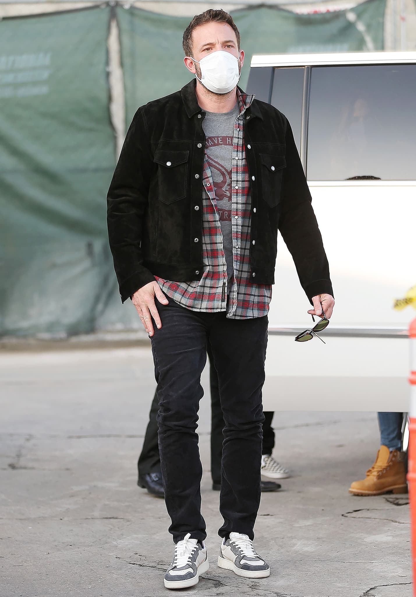 Ben Affleck keeps things casual in a black suede jacket layered over a plaid flannel and graphic tee, finishing the laid-back movie-night look with black jeans and gray-and-white sneakers
