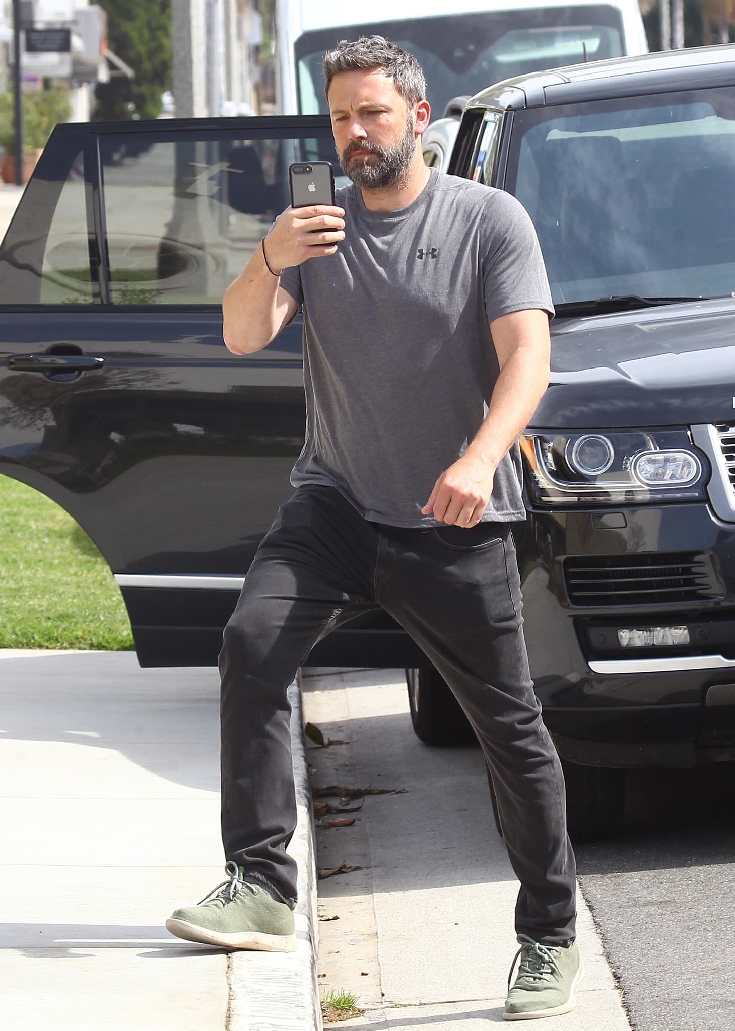 Ben Affleck kept his look understated in an Under Armour performance tee, black denim, and muted green sneakers while stepping out beside a black Range Rover in Los Angeles