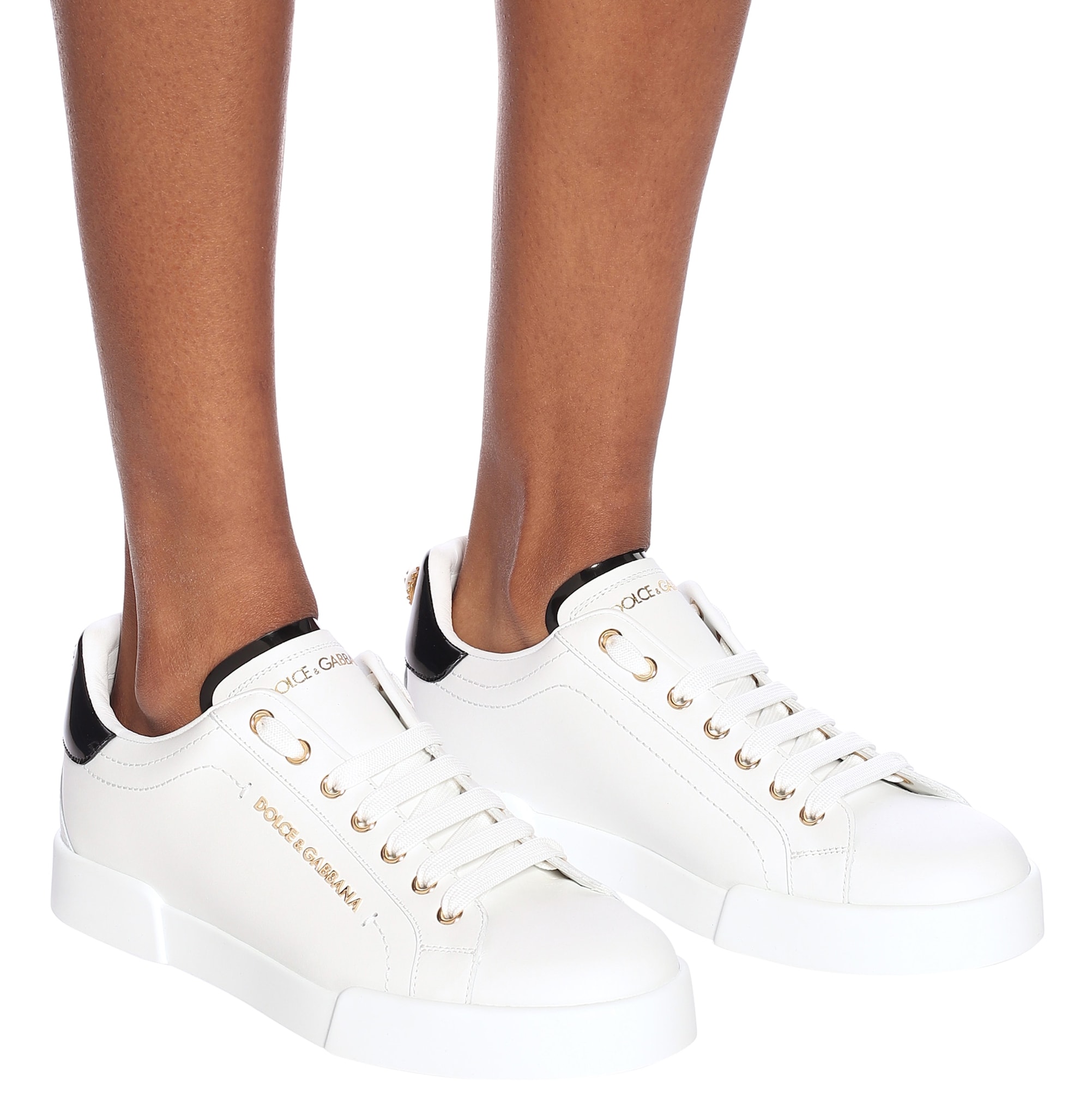 Dolce Gabbana's Portofino sneakers combine crisp white calfskin leather, gold-tone eyelets and branding, and a contrasting black heel tab for a polished take on the everyday luxury sneaker