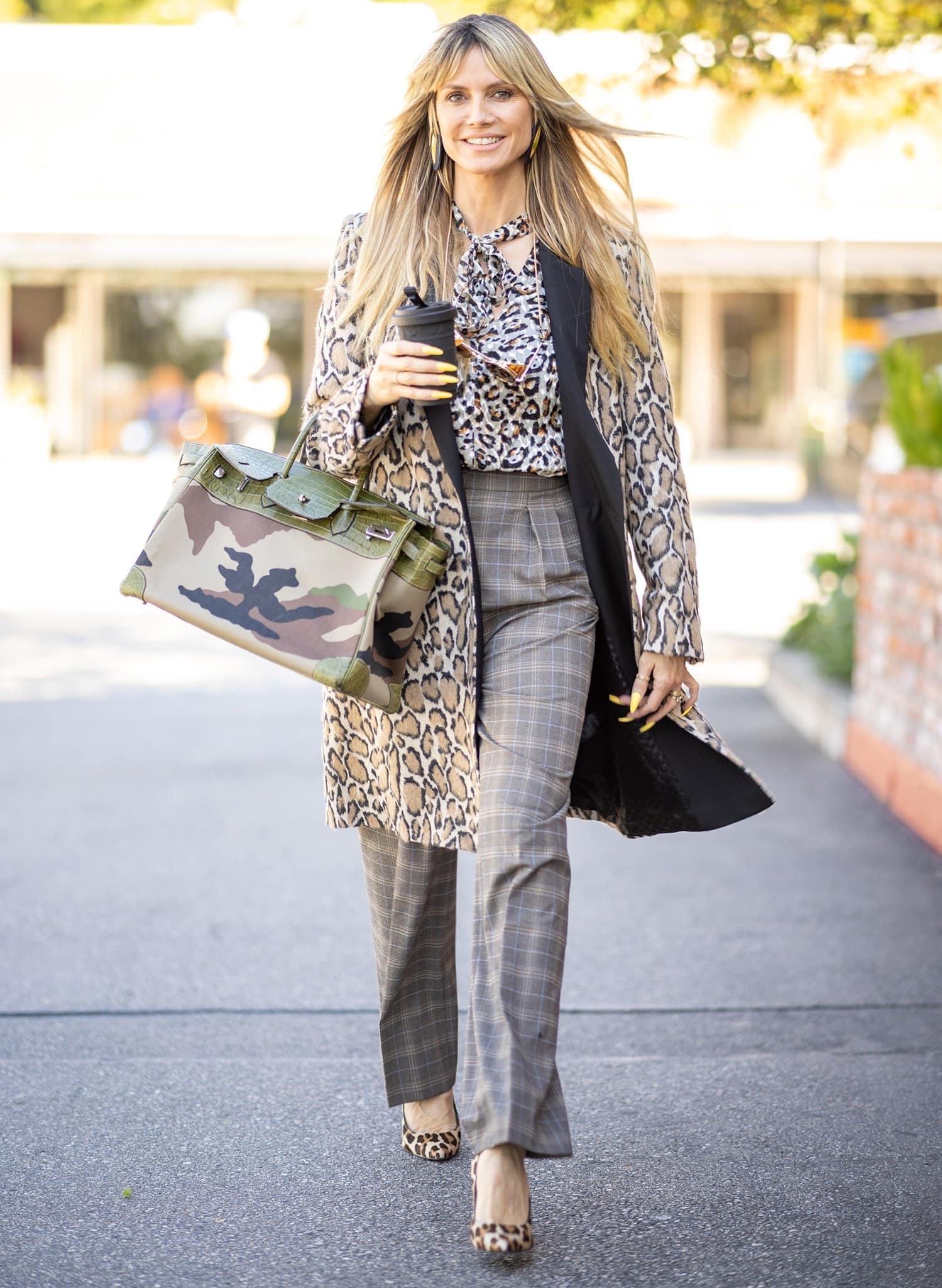 Heidi Klum effortlessly mixes leopard prints, plaid tailoring, and a camouflage Hermès Birkin, letting her striking leopard pumps tie the eclectic look together