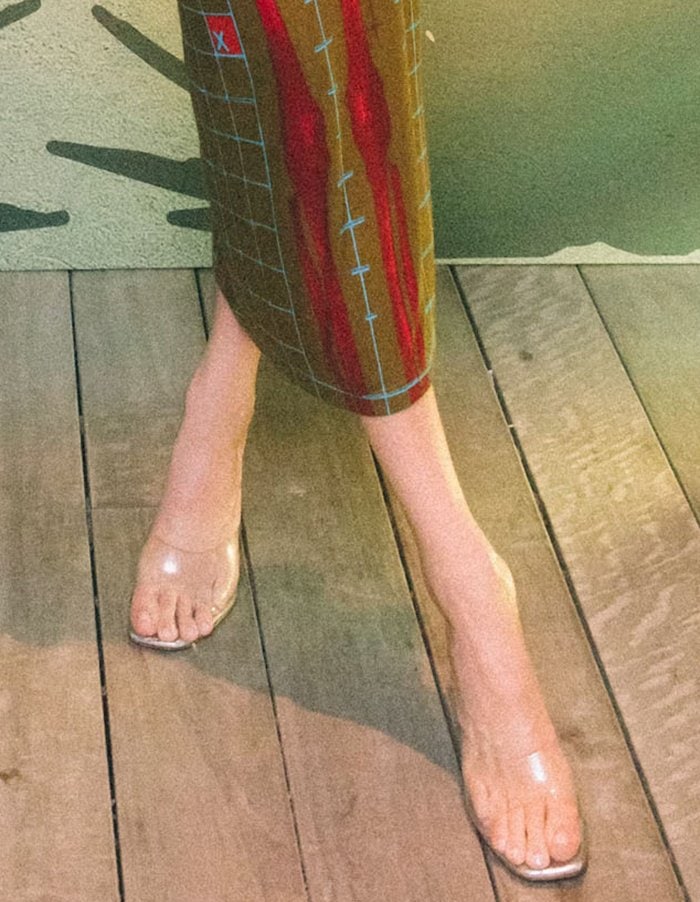 Kendall Jenner completes her festive look with Amina Muaddi Lupita clear PVC mules, whose transparent design creates a leg-lengthening illusion that seamlessly blends with her skin tone