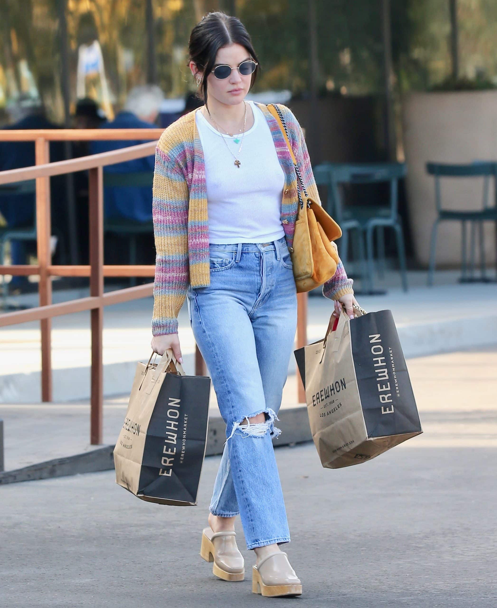 Lucy Hale carries her Erewhon shopping bags in Los Angeles while styling a colorful Line Dot cardigan, light-wash ripped jeans, a mustard-yellow Saint Laurent "Niki" bag, and Rachel Comey "Salta" wooden clogs