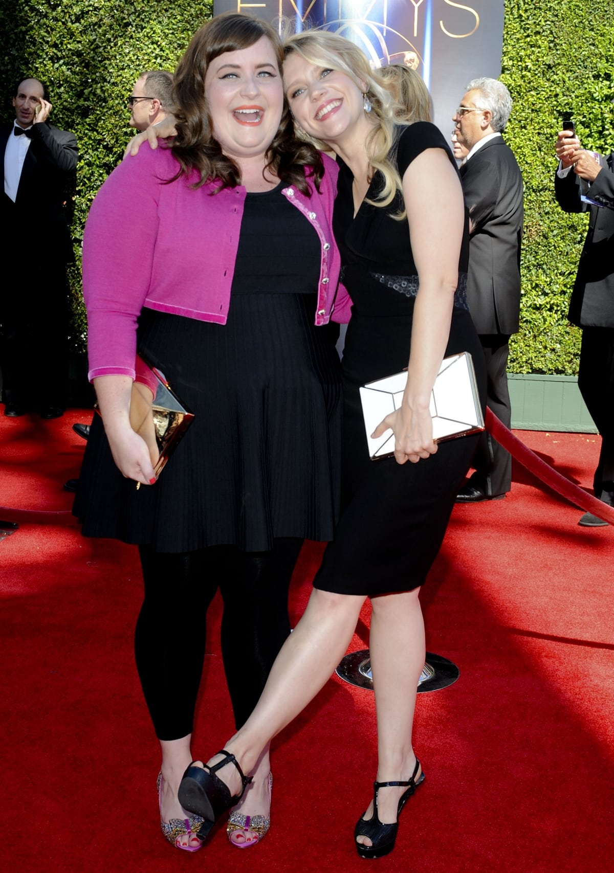 Aidy Bryant and Kate McKinnon attend the 2014 Creative Arts Emmy Awards at the Nokia Theatre L.A. Live in Los Angeles on August 16, 2014 — McKinnon keeps it classic in a black cocktail dress and peep-toe T-strap heels, while Bryant adds a playful pop of color with her fuchsia cardigan and glitter pumps