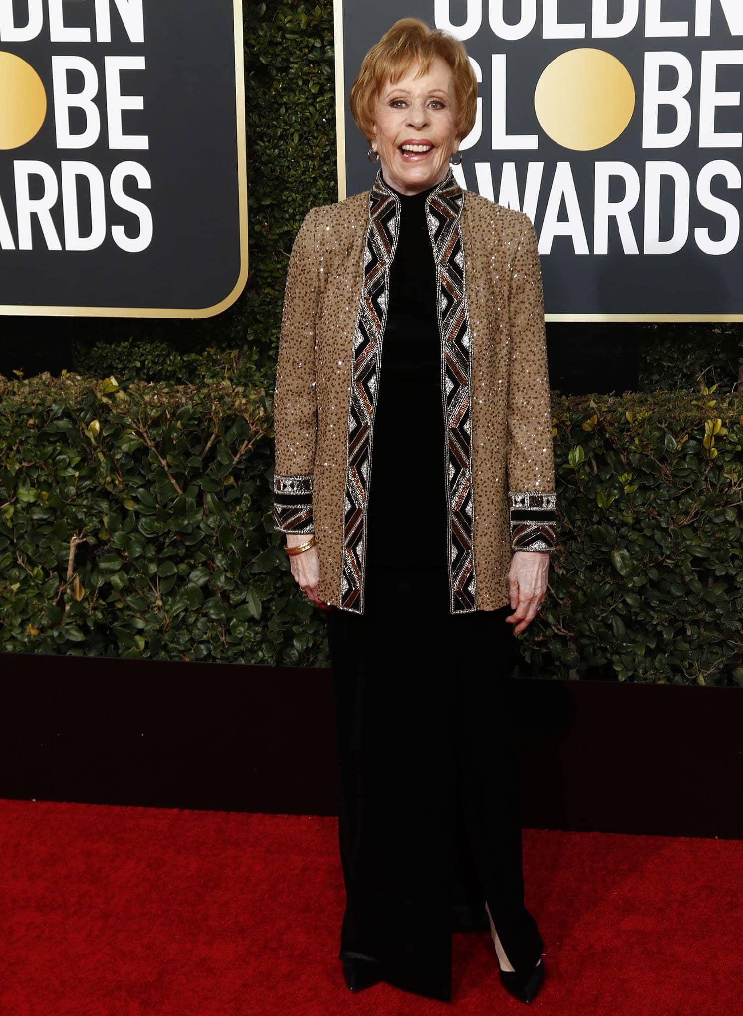 Carol Burnett brings timeless elegance to the Golden Globe Awards in a black velvet ensemble paired with a sparkling embellished jacket, finished with classic pointed-toe heels for a refined and graceful red carpet appearance