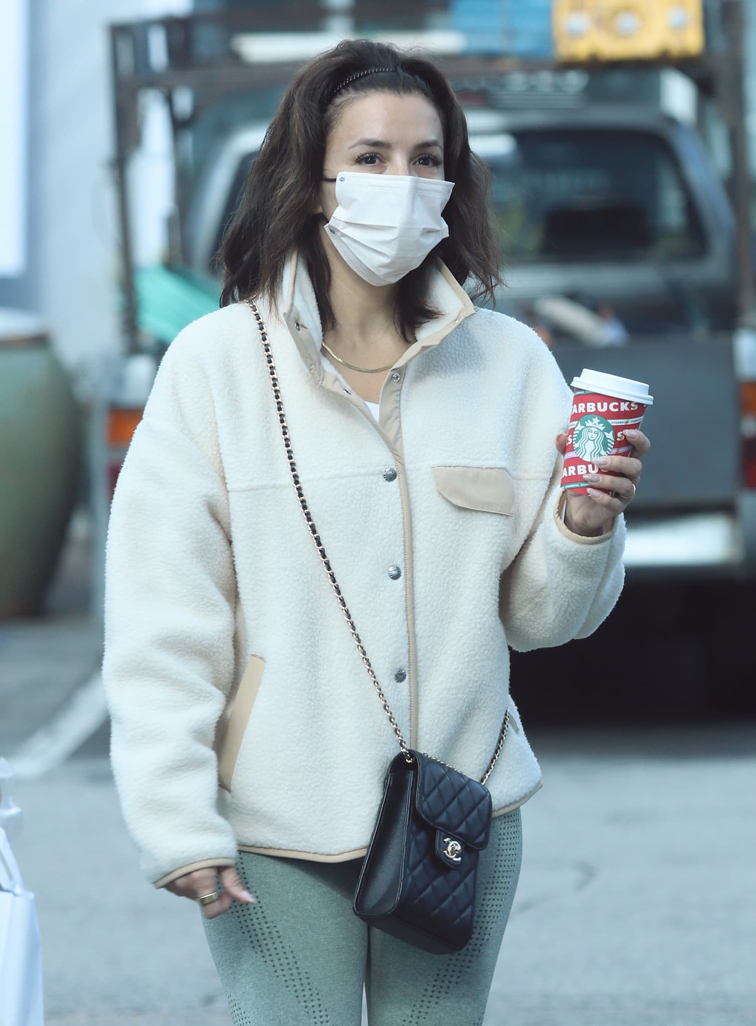 Eva Longoria keeps her off-duty look polished and practical, pairing a cozy cream fleece with sculpting leggings and a quilted Chanel crossbody while carrying a coffee on a casual Beverly Hills outing