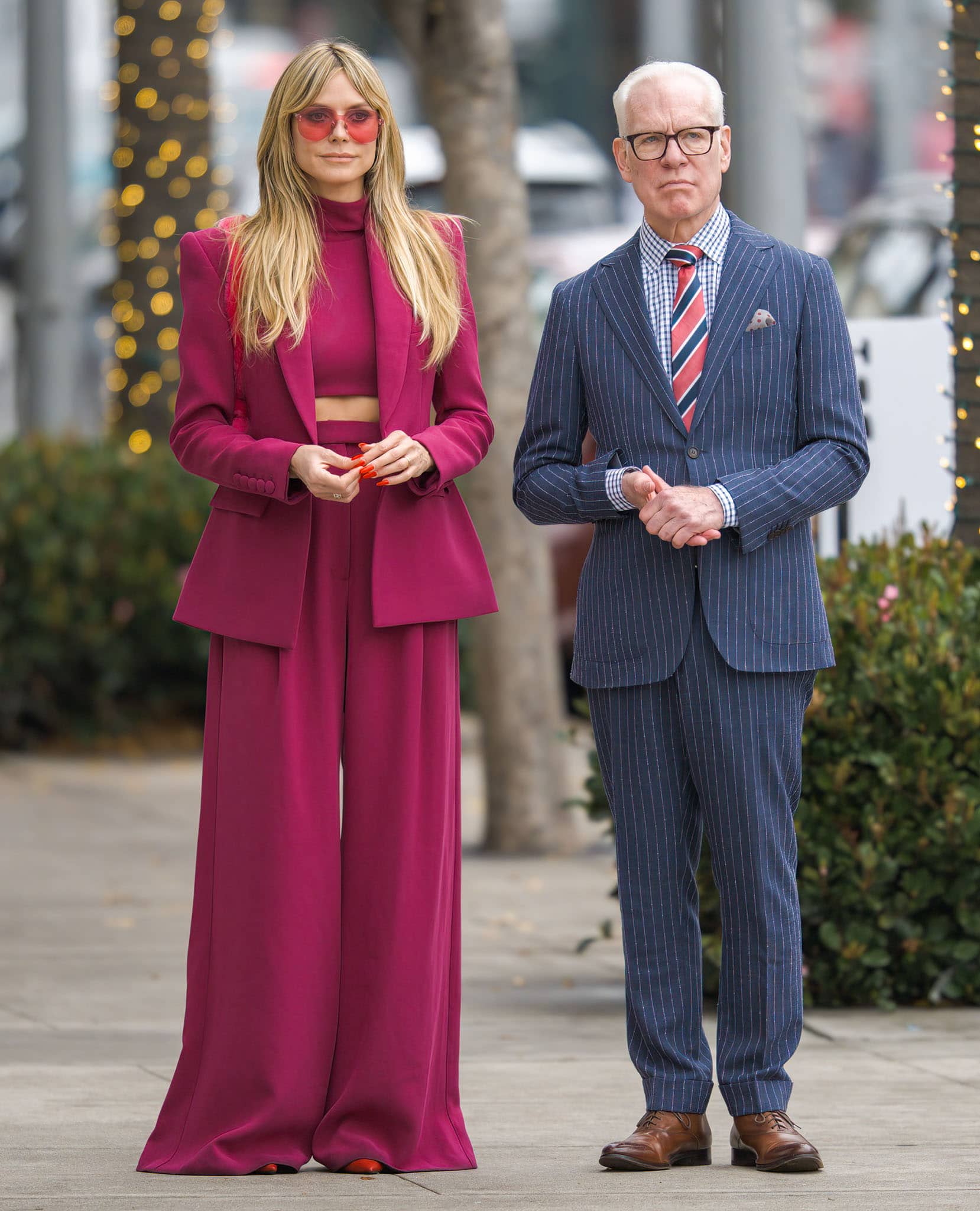 Heidi Klum films Making the Cut with Tim Gunn on Rodeo Drive in Beverly Hills on January 17, 2022, wearing a fuchsia pantsuit, red Christian Louboutin So Kate patent pumps, a pink Moschino bag, and rose-tinted aviator sunglasses