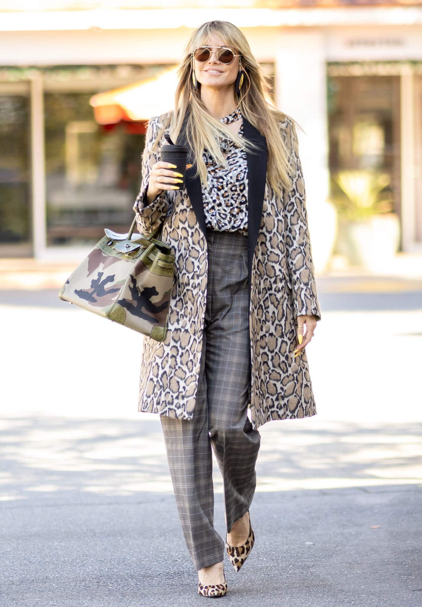 Heidi Klum effortlessly masters mixed prints with a bold leopard coat, matching heels, and a camouflage handbag, blending patterns with confidence