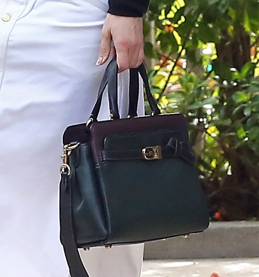 Jennifer Lopez elevates her monochrome Hotel Bel-Air look with a structured black Coach Tate carryall, featuring polished gold hardware and a sleek top-handle silhouette that complements her tailored black-and-white styling