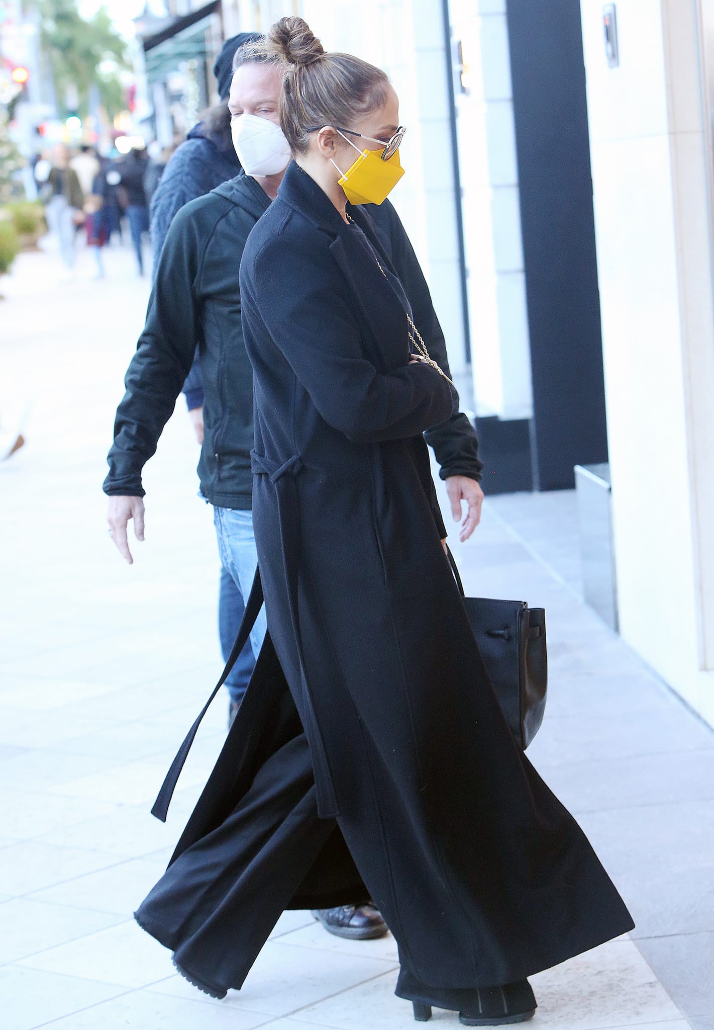 Jennifer Lopez steps out in a flowing black wrap coat, wide-leg trousers, and chunky platform boots, anchoring her monochromatic street-style look with bold, grounded footwear