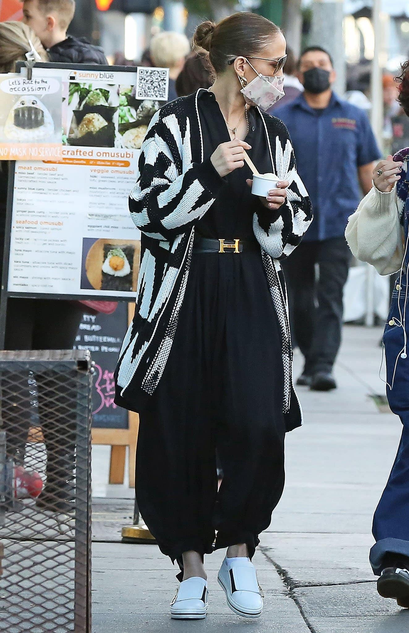 Jennifer Lopez teams her jumpsuit with white slip-on shoes, Hermès Birkin bag, Hermès belt and a Henry Divine face mask