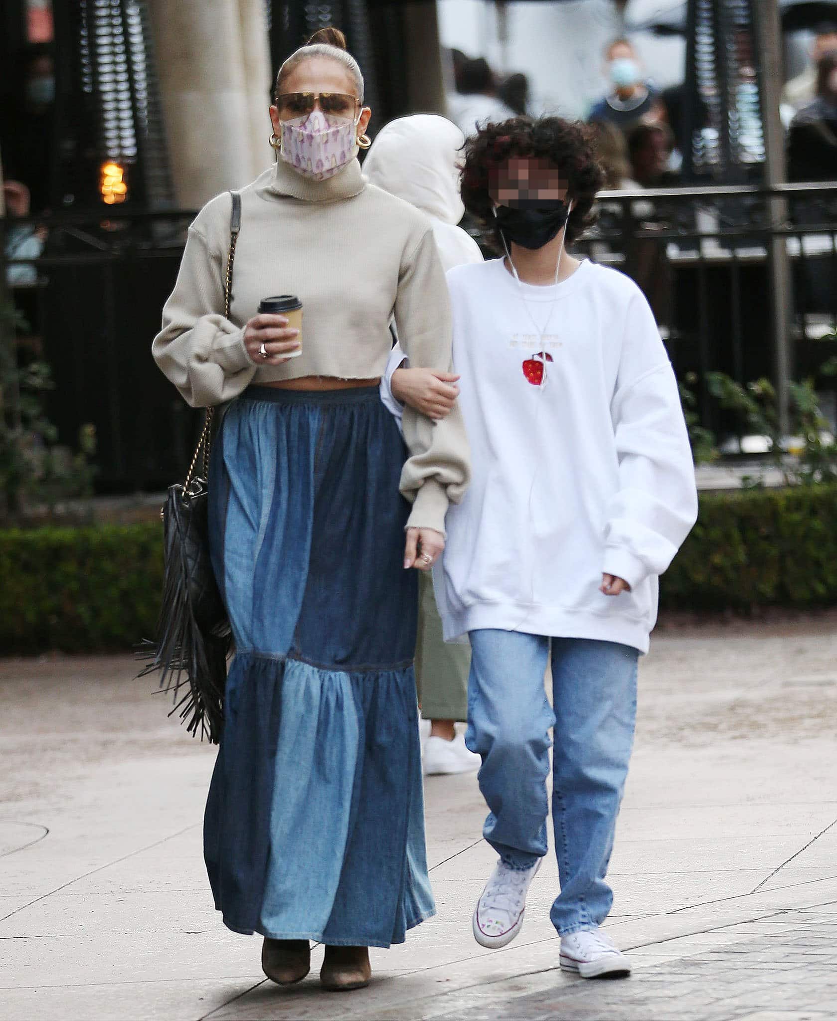 Jennifer Lopez's daughter Emme pairs an oversized white sweater with loose-fitting jeans and white Converse sneakers