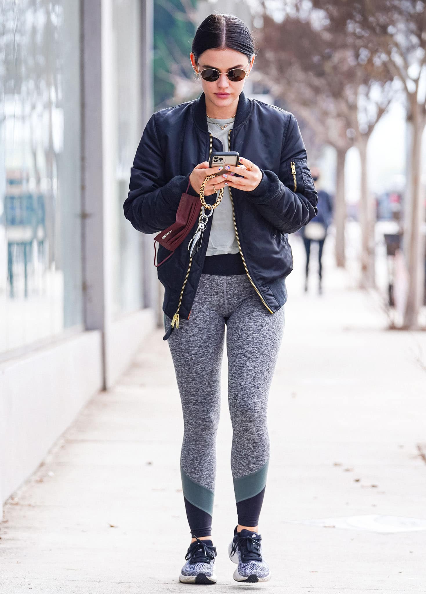 Lucy Hale perfects off-duty athleisure by pairing a gray tee and color-blocked leggings with a navy bomber jacket and sleek performance sneakers for an effortlessly polished street-style look