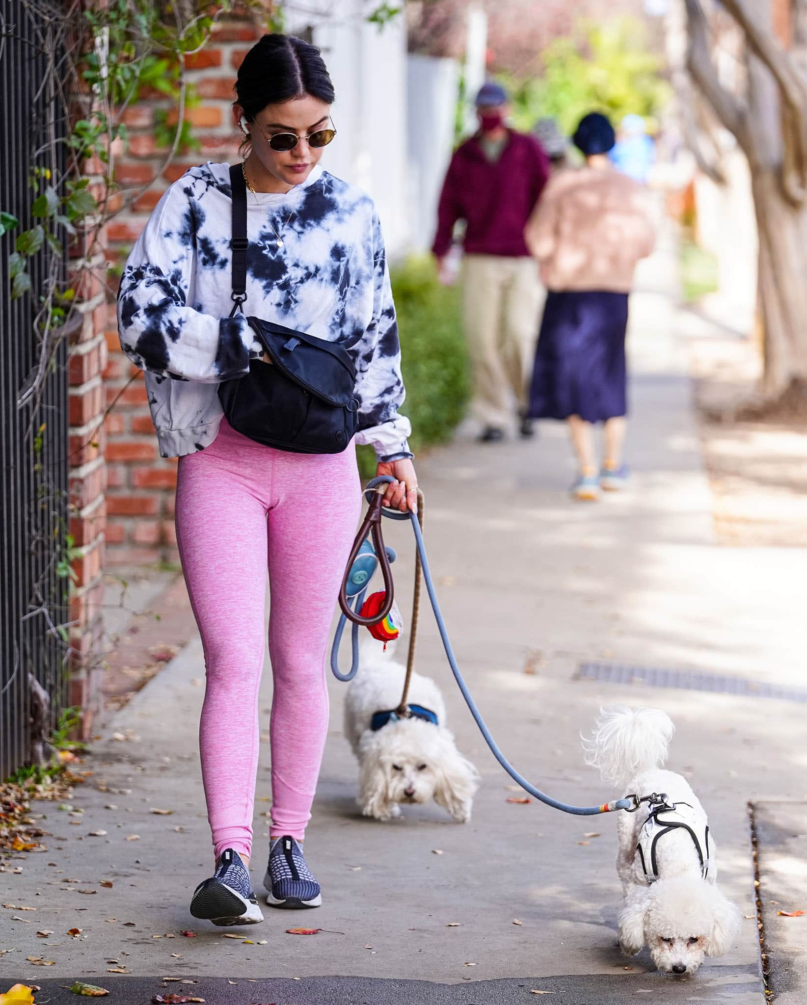 Lucy Hale takes Elvis and Ethel for a walk in Los Angeles on January 12, 2022, leaning into sporty athleisure with a tie-dye sweatshirt, pink leggings, and performance sneakers that balance comfort and street-ready style