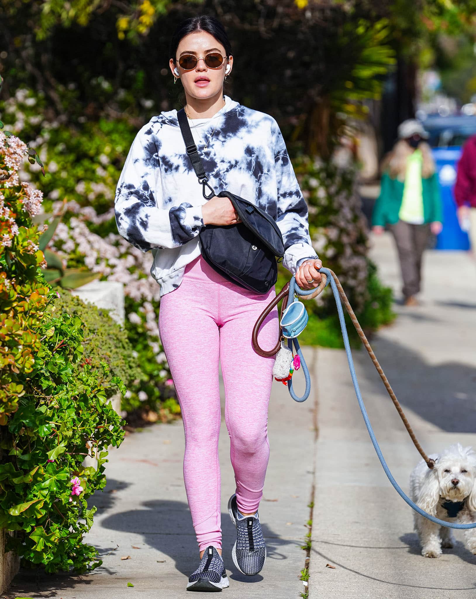 Lucy Hale brightens her off-duty look by pairing a blue-and-white tie-dye hoodie with pink leggings and sporty sneakers, striking an easy balance between comfort, color, and everyday athleisure style
