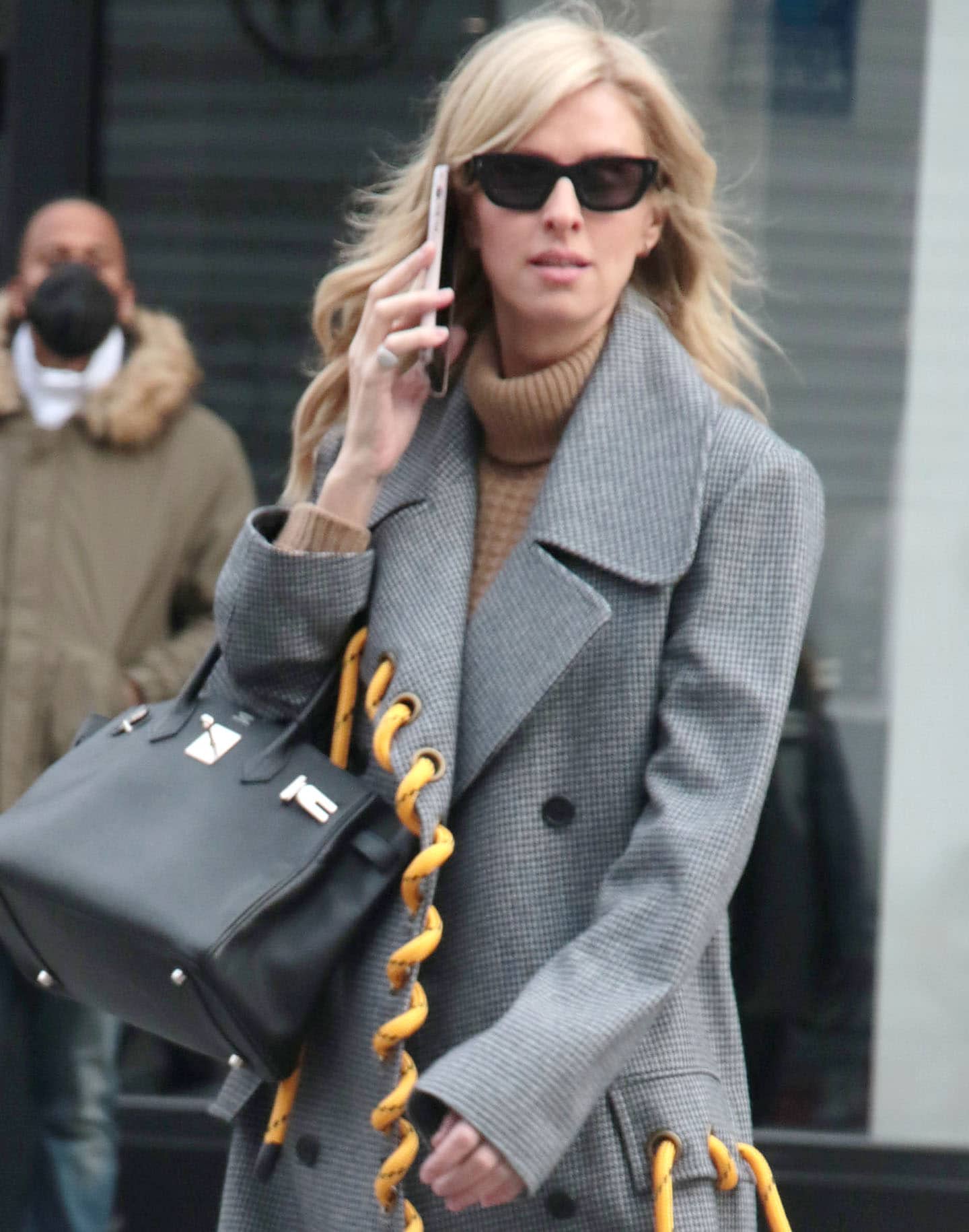 A black Hermès Birkin with gold hardware adds a classic luxury counterpoint to Nicky Hilton’s unconventional rope-trimmed Monse coat