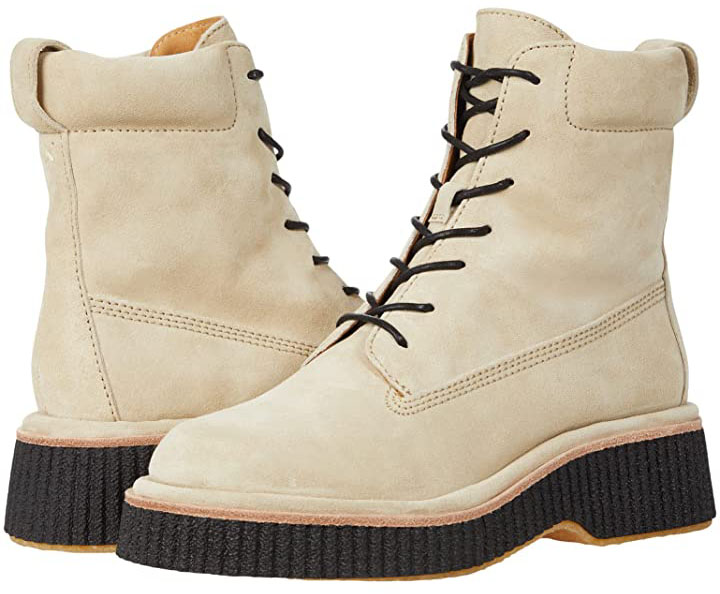 The Rag Bone “Sloane” boot in cream suede pairs a structured lace-up upper with a padded collar and signature flared crepe sole, delivering a cushioned, slightly elevated platform that blends utilitarian grip with refined, city-ready polish